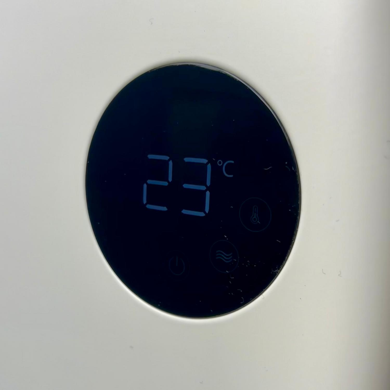 Ein digitales Display zeigt 23°C in Blau auf einem schwarzen kreisförmigen Bildschirm. Der Hintergrund ist weiß.