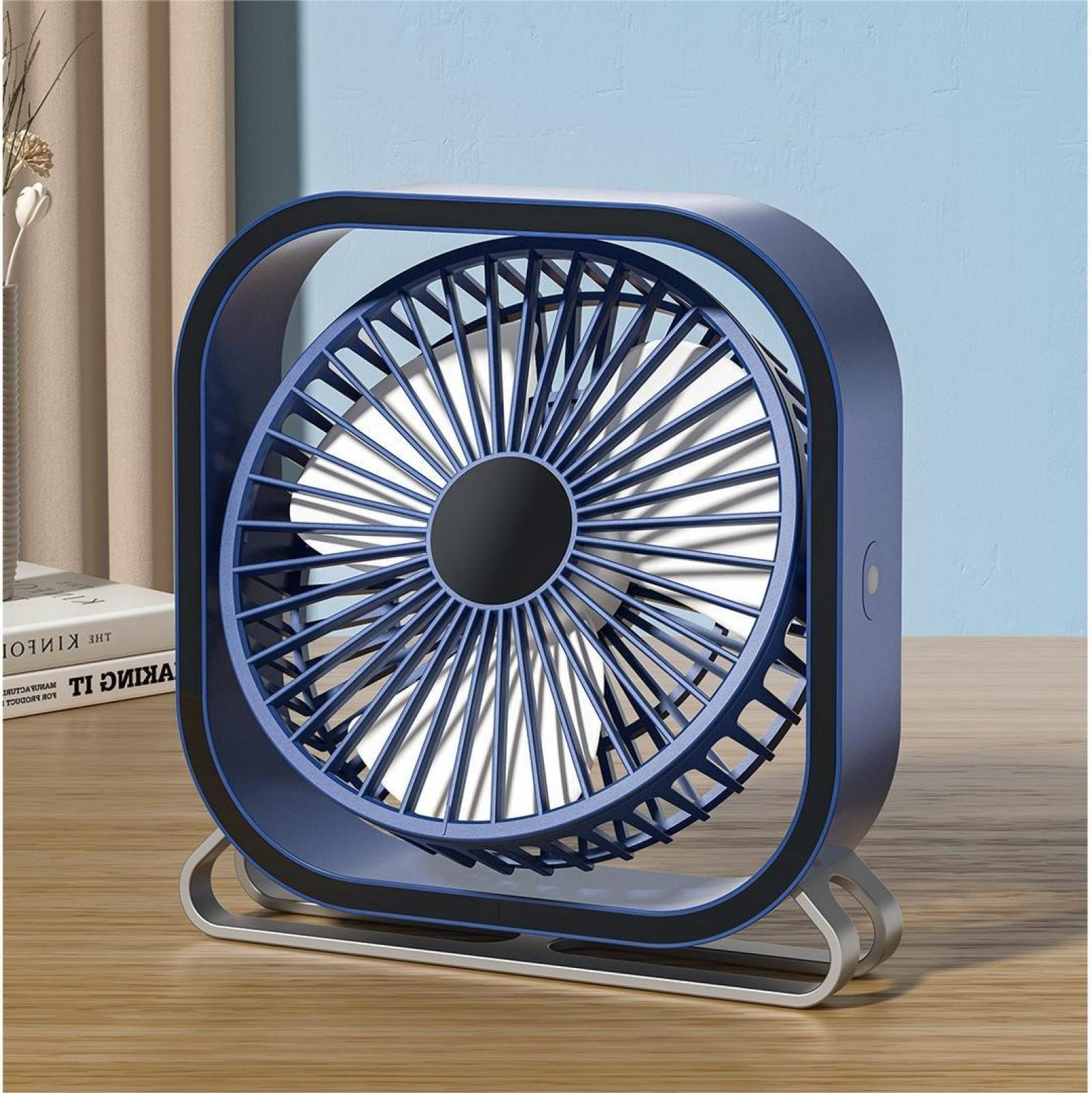 Ein blauer und schwarzer quadratischer Ventilator steht auf einer Holzoberfläche. Im Hintergrund sind eine Wand, Bücher und ein Vorhang.