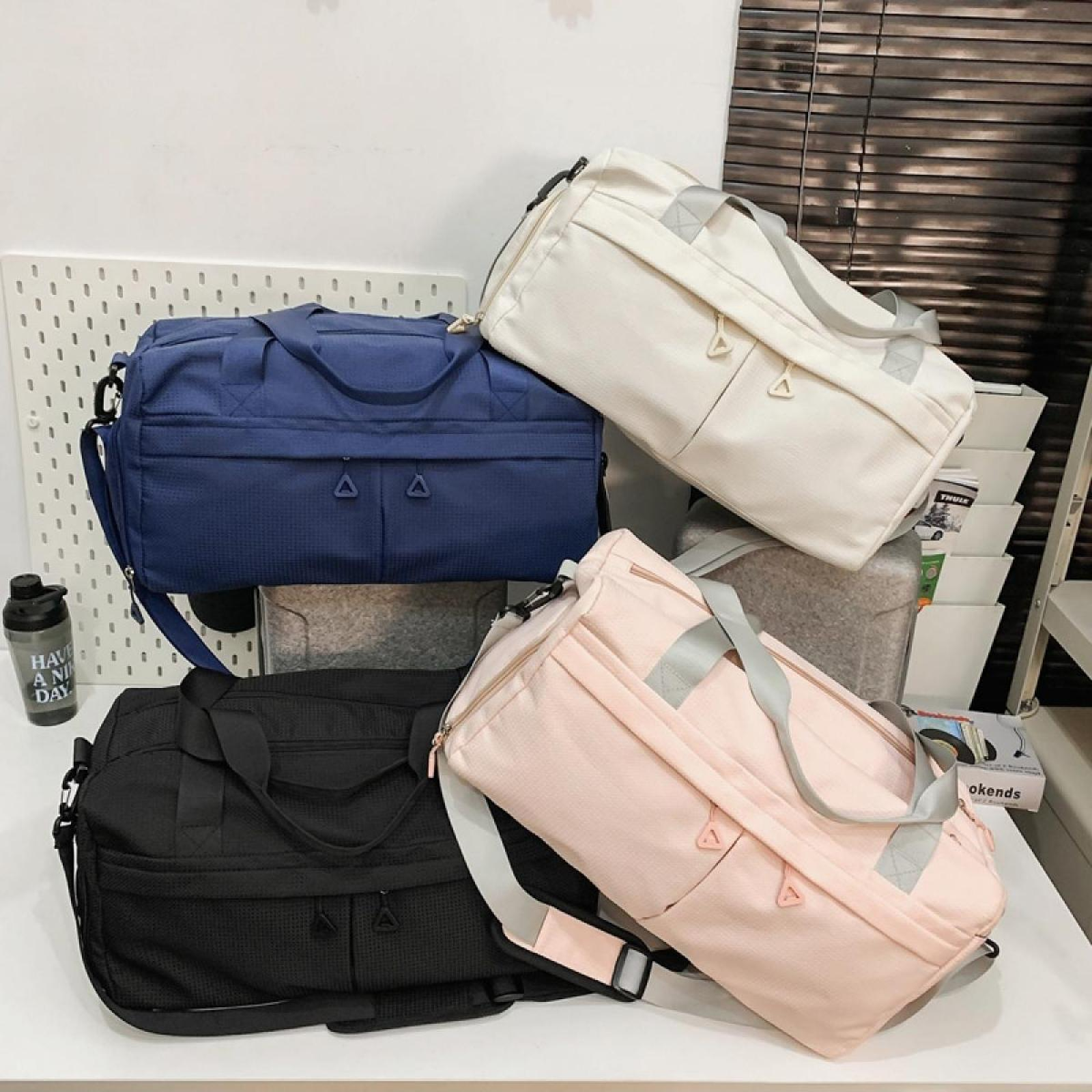 Vier Reisetaschen in verschiedenen Farben: Schwarz, Blau, Rosa und Weiß, angeordnet auf einer weißen Oberfläche.