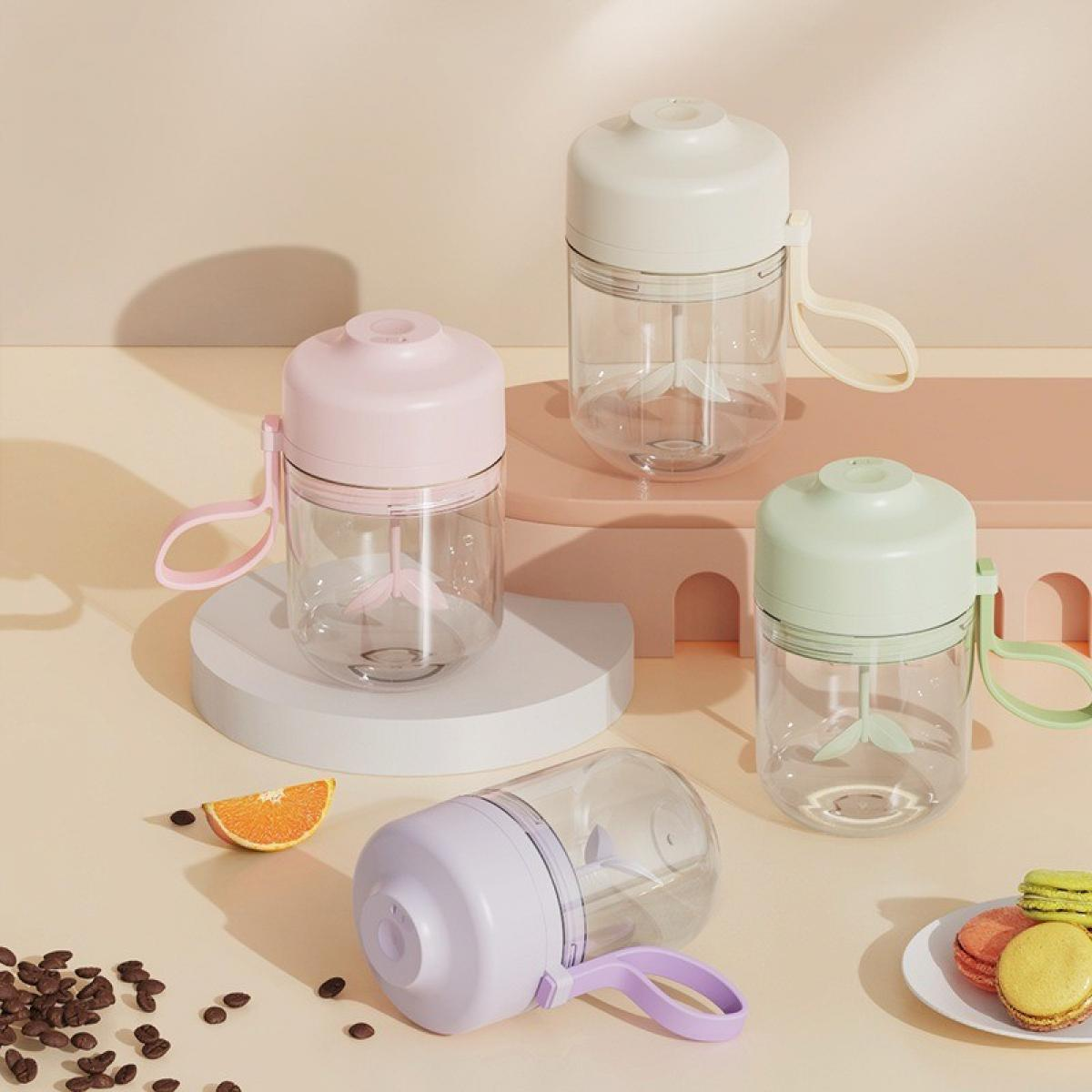 Vier farbige Mixer, einer horizontal. Außerdem eine Orangenscheibe, Makronen und Schokolade auf pastellfarbenem Hintergrund.
