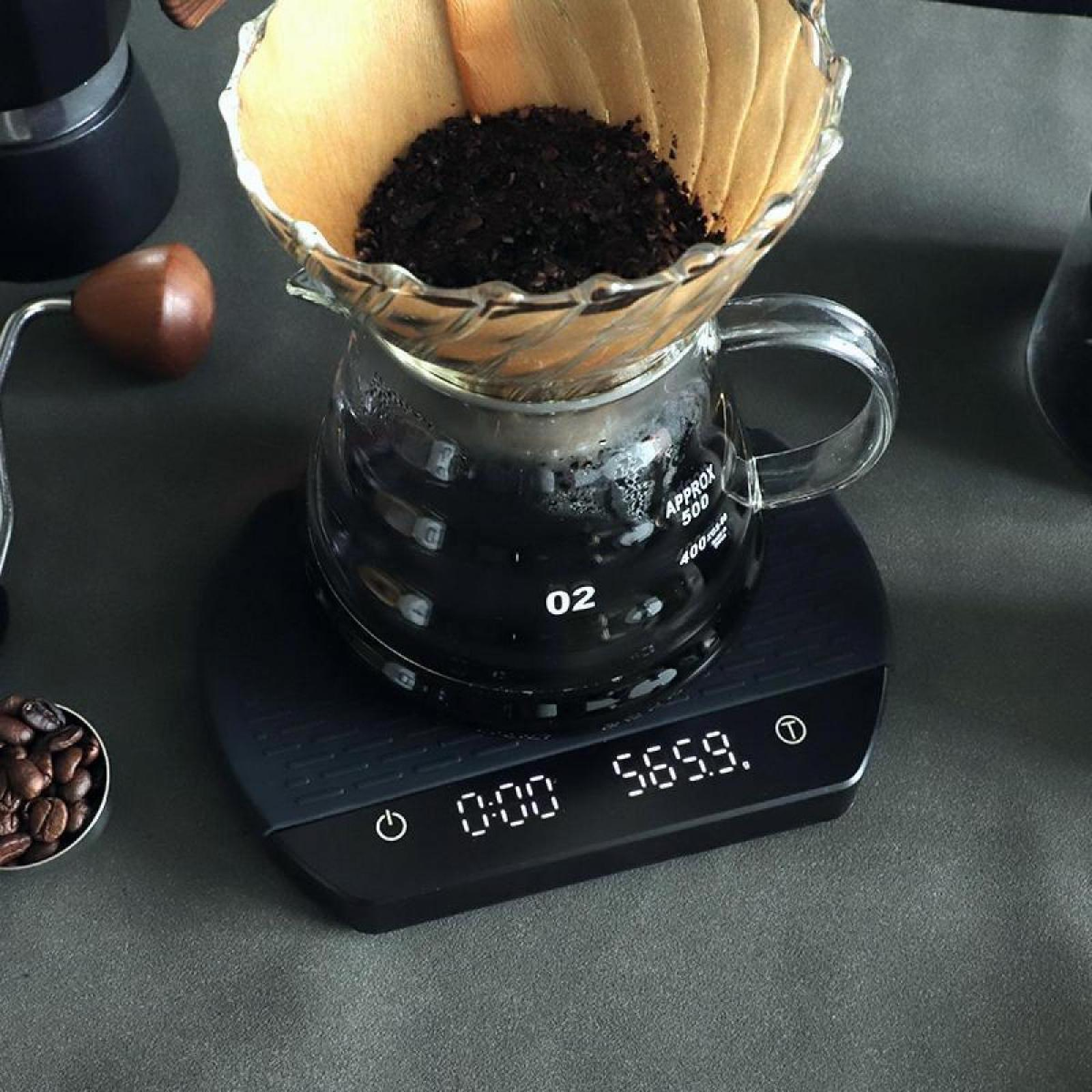 Ein Kaffeeaufbau mit einer Glaskaraffe auf einer Waage, einem Filter mit Kaffeepulver und Bohnen.