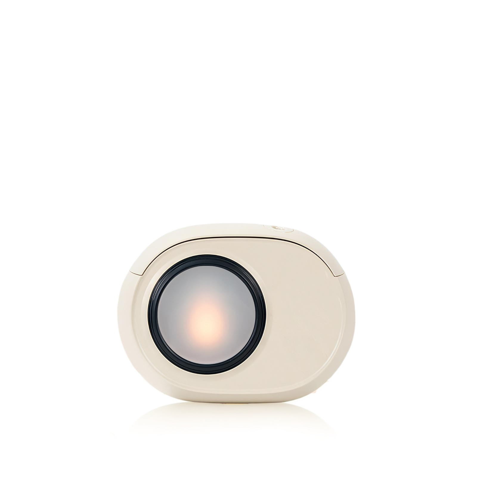 Ein beiges, ovales Gerät mit einer zentralen, runden Lichtquelle. Es hat einen schwarzen Ring um das Licht und liegt auf weißem Grund.