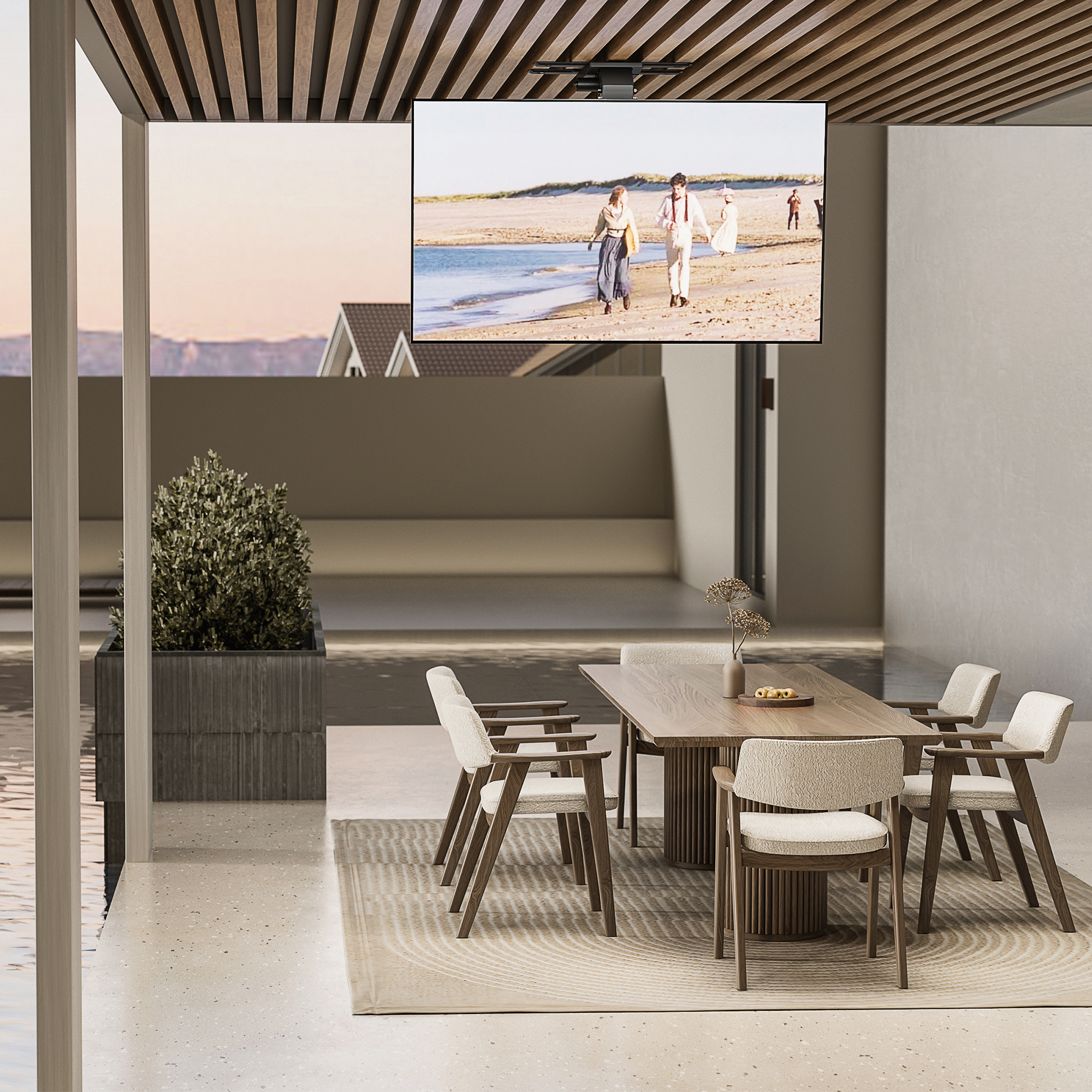 Essbereich im Freien mit einem Fernseher, der Menschen an einem Strand zeigt. Tisch und Stühle sind gedeckt, Pflanze und Pool sichtbar.