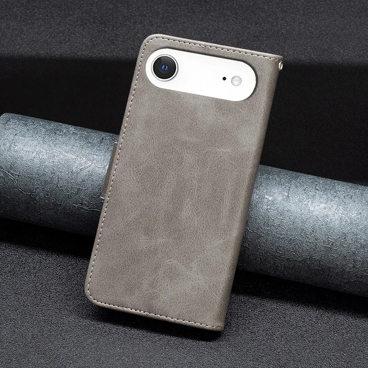 Un étui de téléphone gris avec une découpe pour l'appareil photo. L'étui est sur une surface sombre et texturée avec un objet cylindrique.