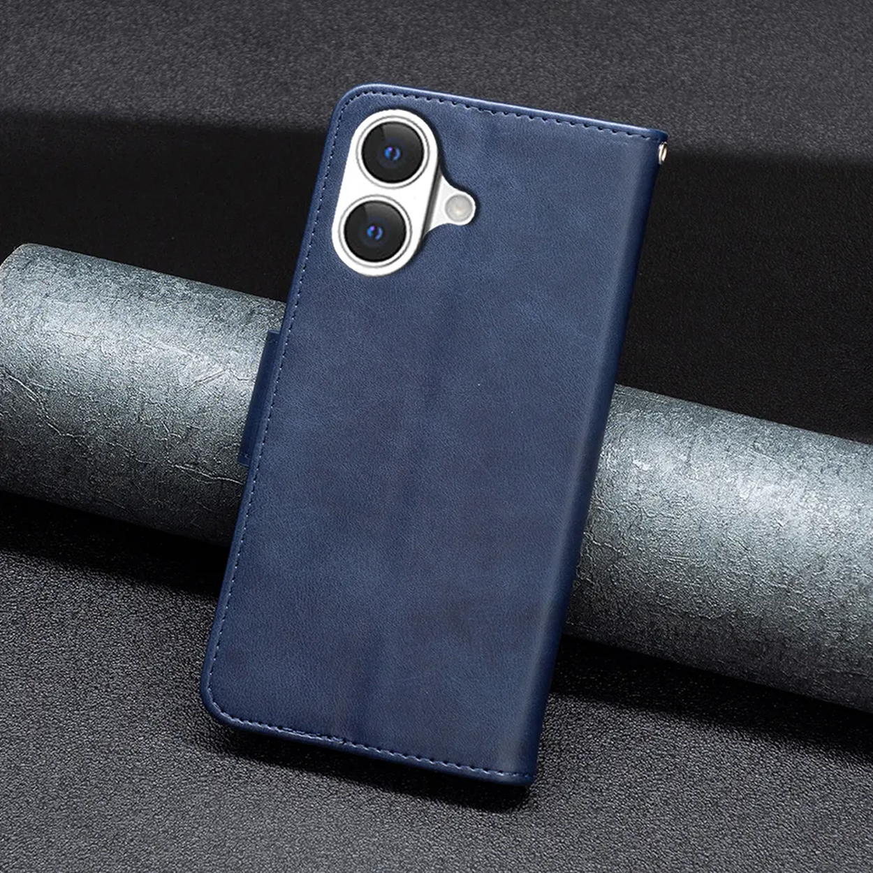 Een blauwe telefoonhoes met een uitsparing voor de camera ligt op een gestructureerd oppervlak met een grijs, opgerold object op de achtergrond.