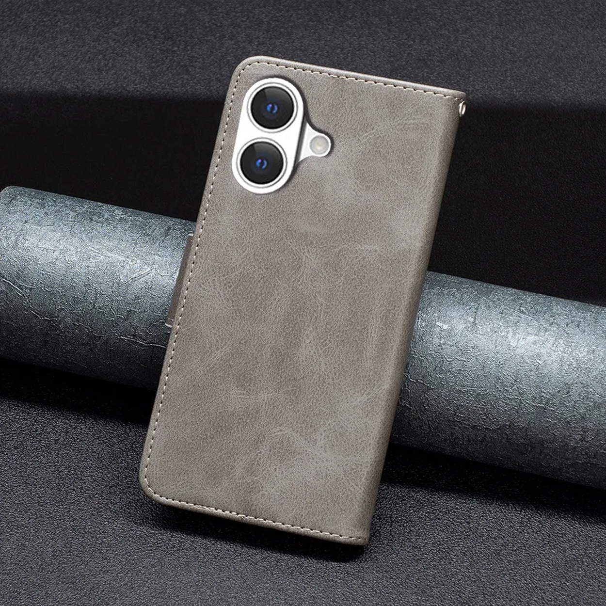 Een grijze leren telefoonhoes met twee cameralenzen. Op een donker oppervlak met een metalen rol.