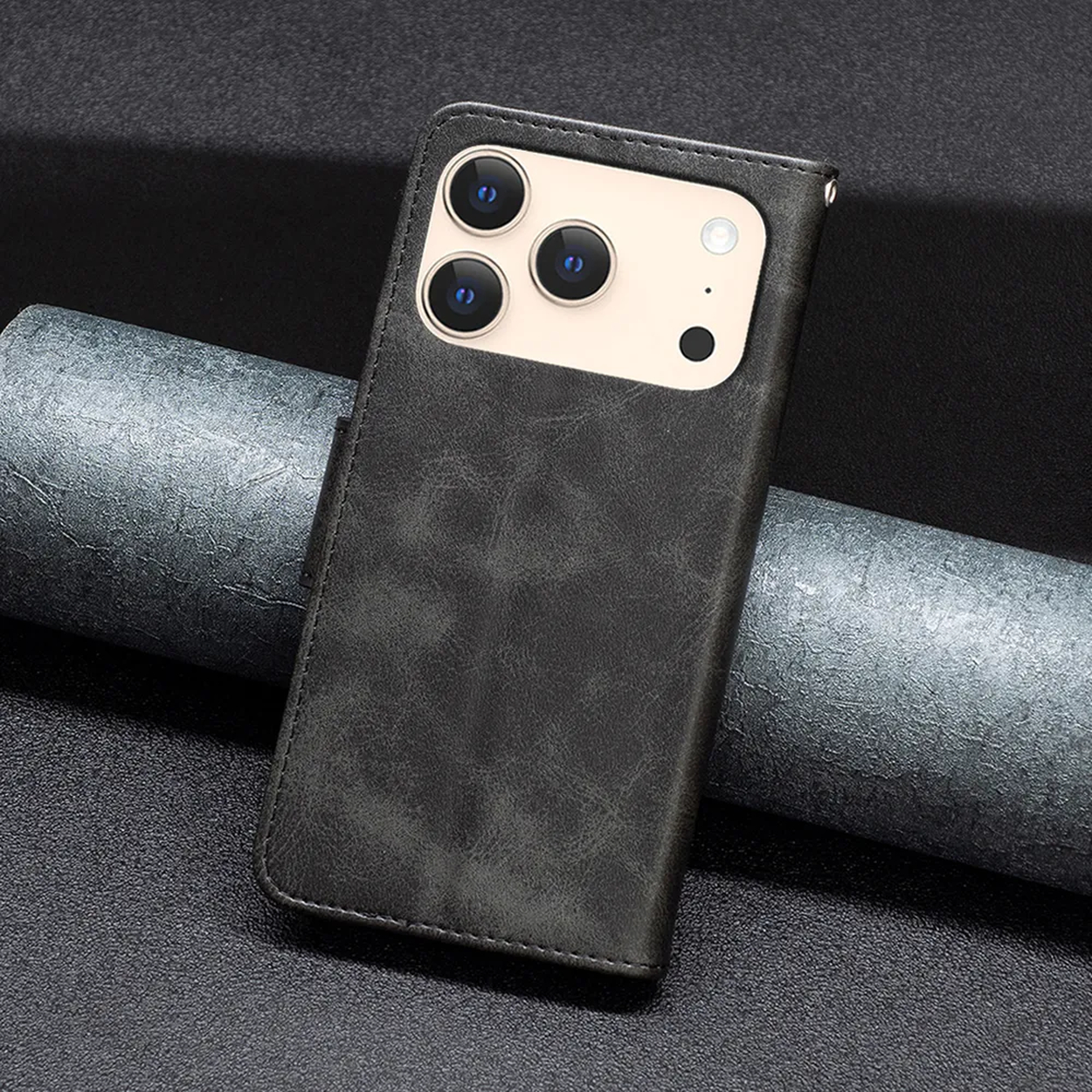 Un étui de téléphone gris avec trois lentilles de caméra. L'étui est sur un fond gris texturé avec un objet gris foncé roulé.