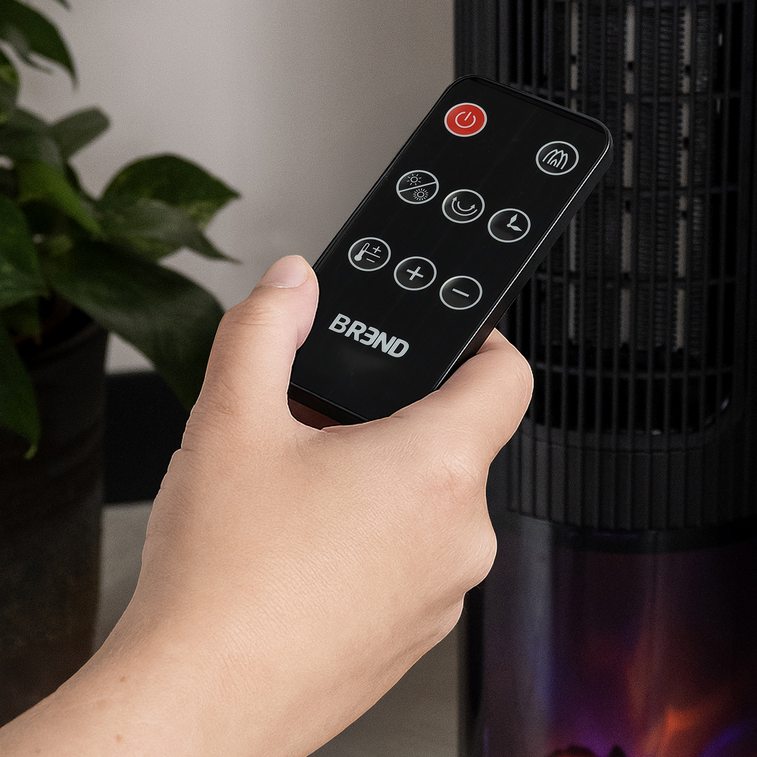 Hand holding a black remote control with white symbols and buttons. A heater is in the background.