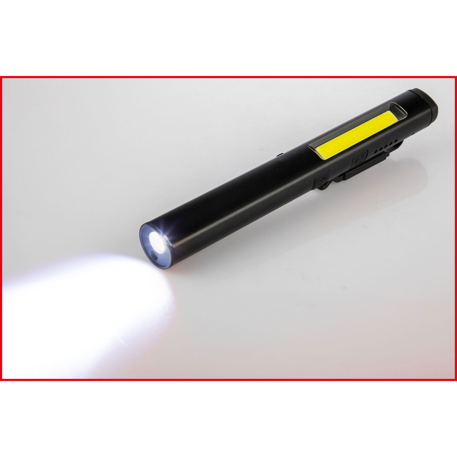 Eine schwarze Taschenlampe mit gelbem Lichtpaneel liegt auf weißem Untergrund. Die Lampe strahlt helles Licht aus.