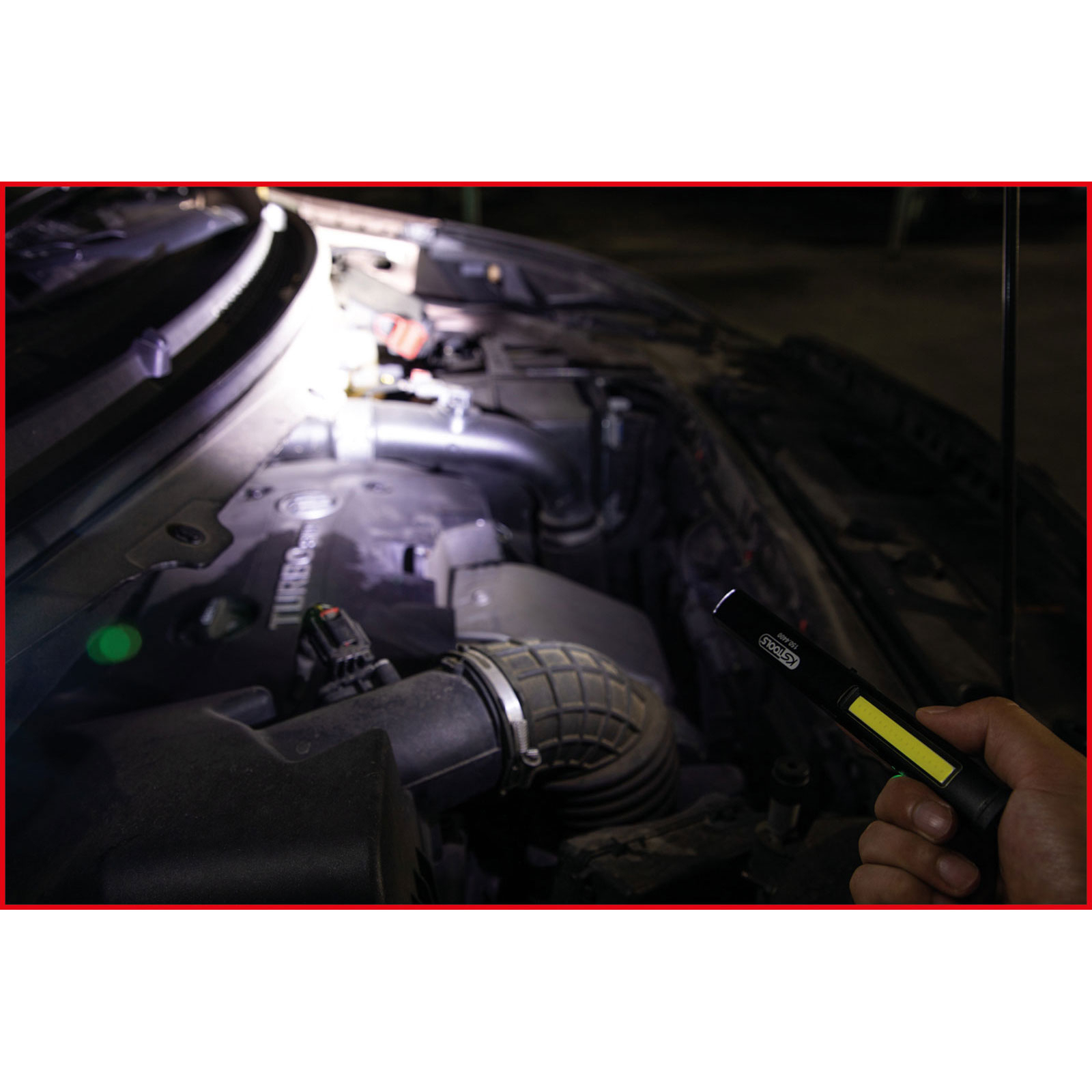 Eine Hand hält eine Taschenlampe und beleuchtet einen Automotor. Die Motorhaube ist geöffnet und gibt Motorkomponenten frei.