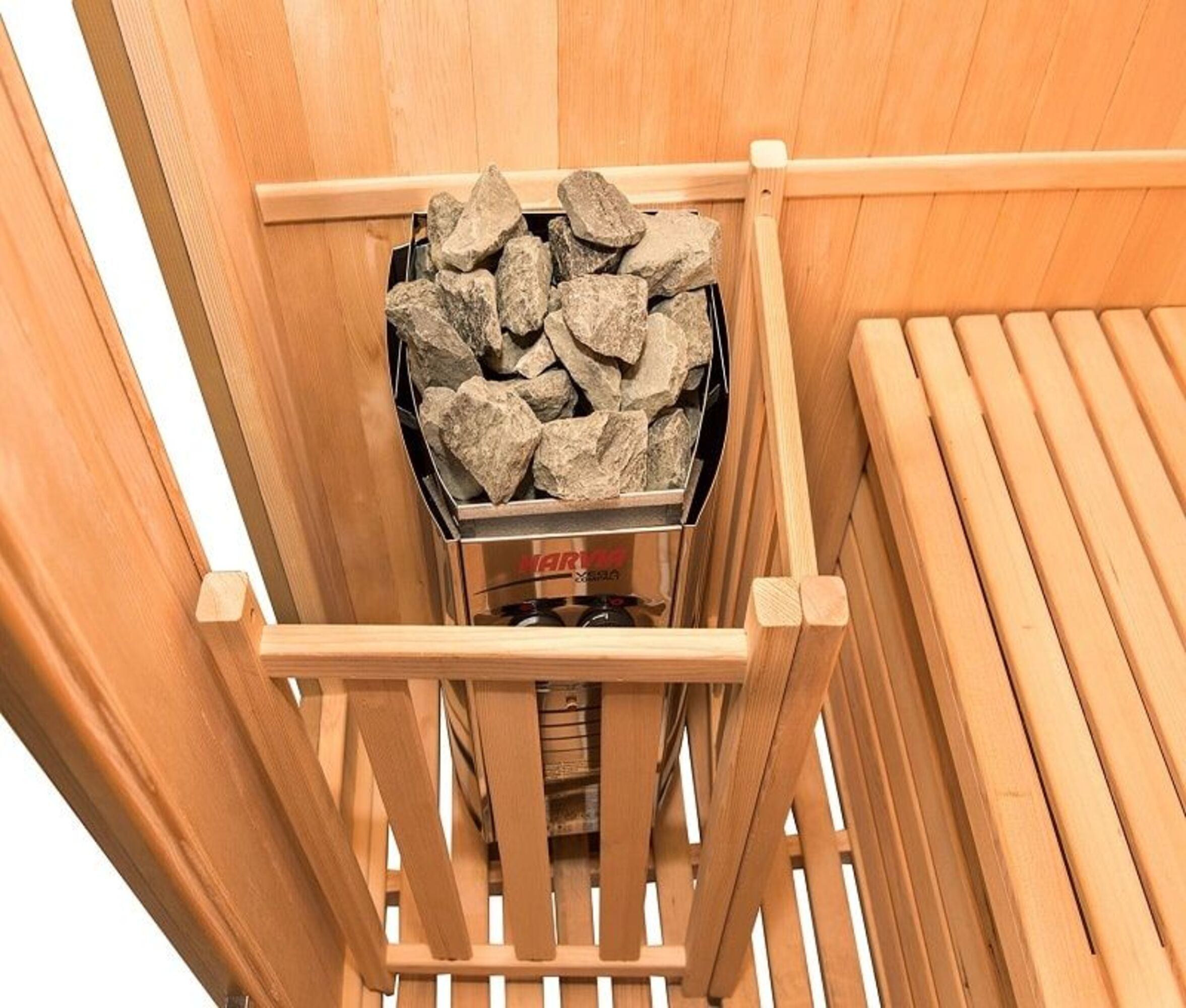 Un interior de sauna de madera con un calentador lleno de rocas. Bancos y paredes de madera completan la escena.