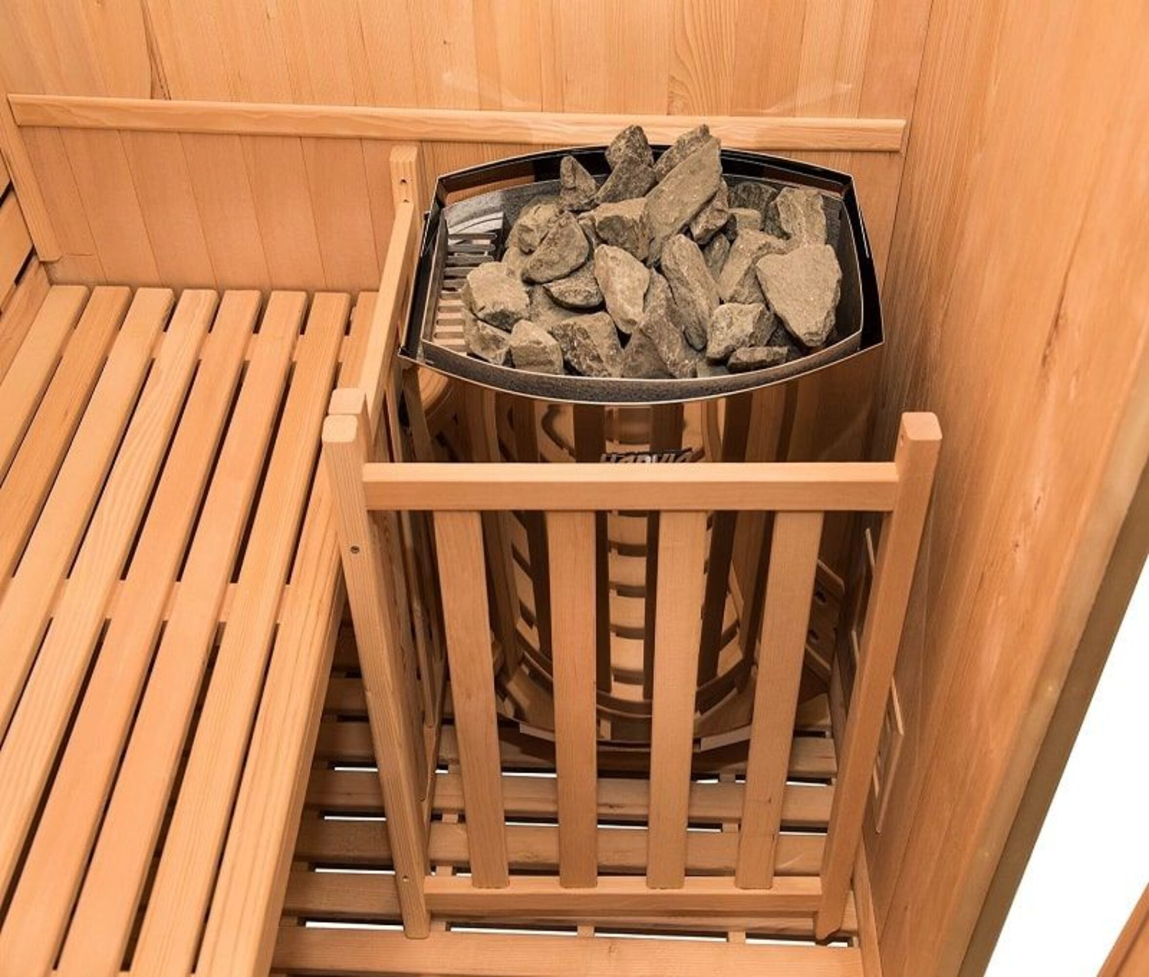 Interior de sauna de madera con calentador de piedras y bancos de madera.