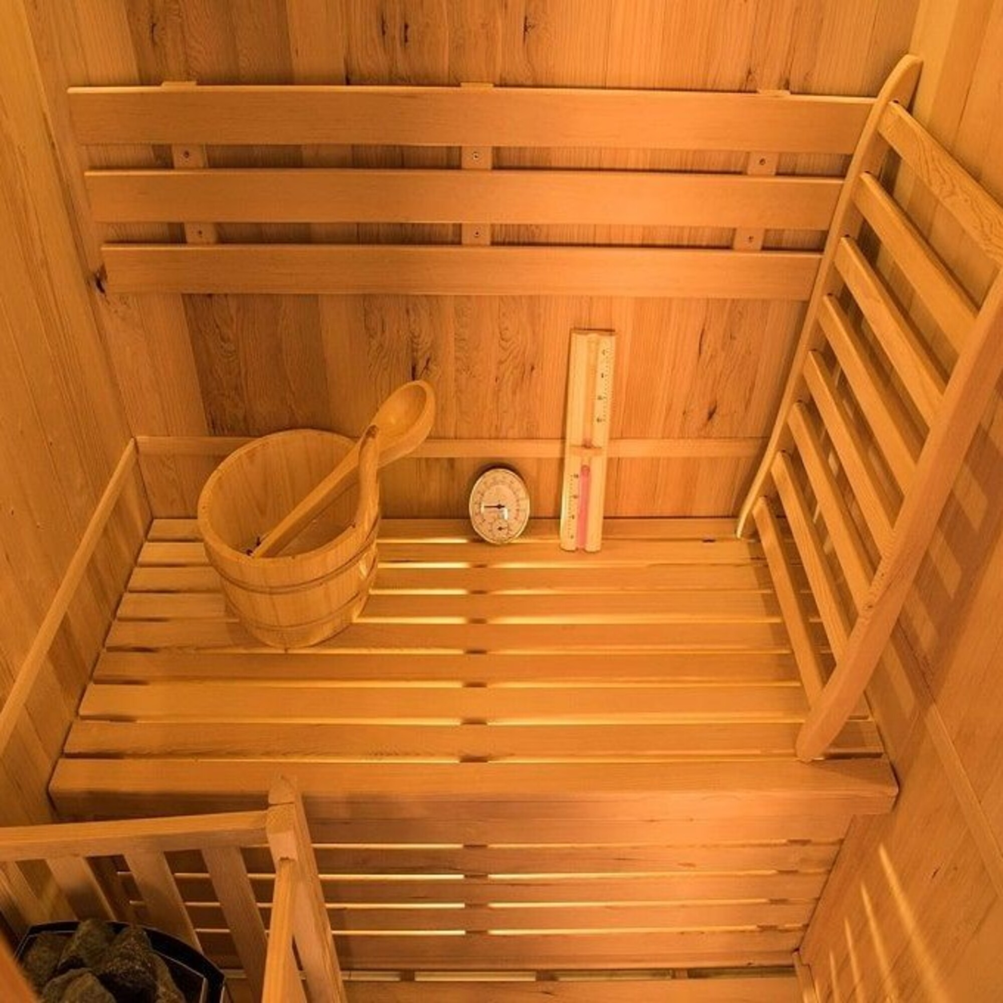 Interior de sauna de madera. Incluye cubo y cucharón, termómetro y bancos de listones.