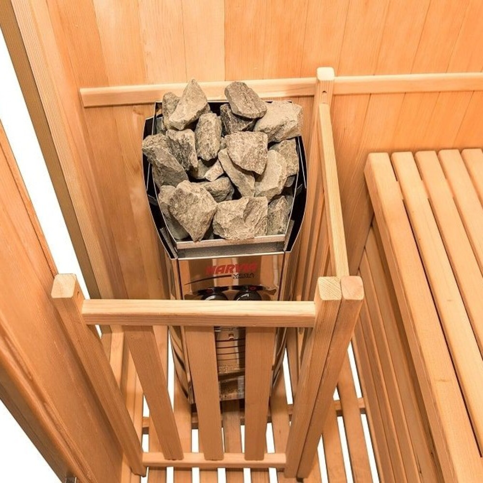 Interior de sauna con bancos de madera y un calentador con rocas. La escena está iluminada con luz cálida.