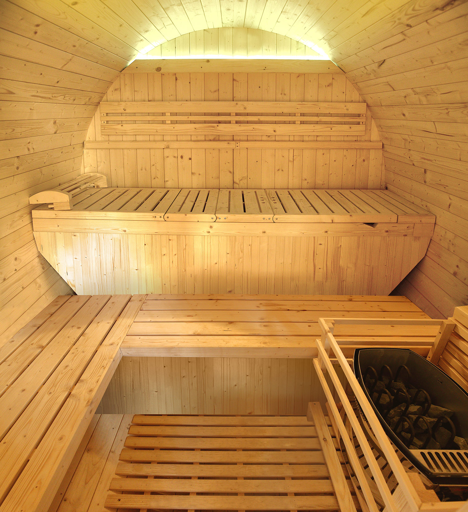 Interior de una sauna de madera. Bancos de listones, paredes y techo de madera, con un calentador que contiene piedras en la esquina.