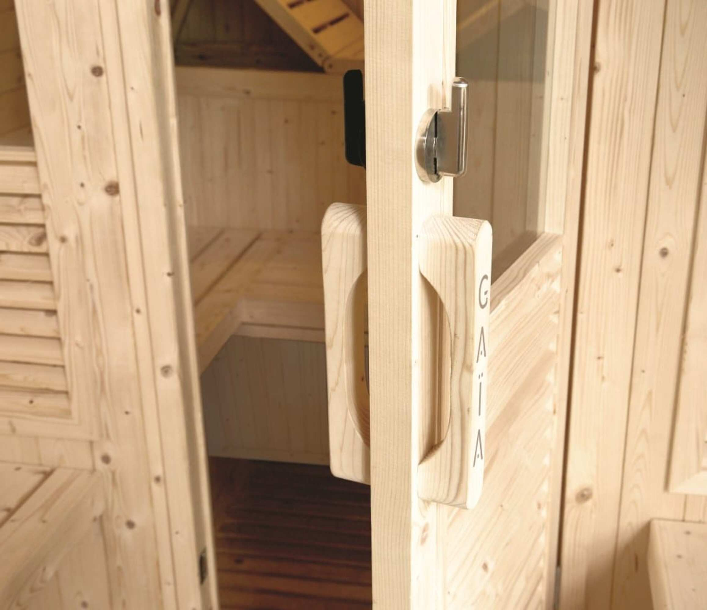 Puerta de sauna de madera parcialmente abierta, mostrando bancos interiores. El tirador dice 'GAIA'.