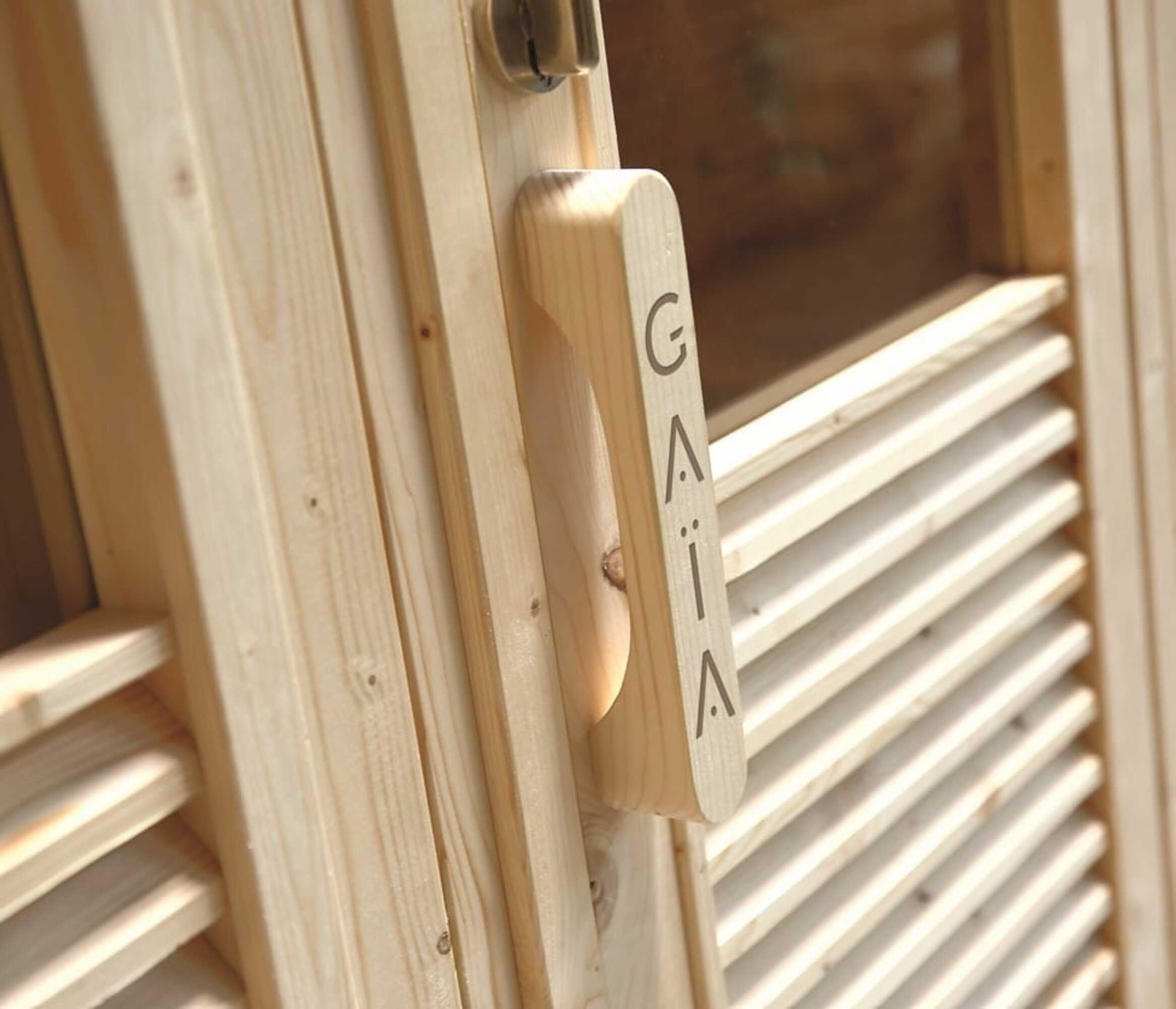 Manija de puerta de madera con el nombre 'GAIA' grabado. La puerta tiene un panel de madera.