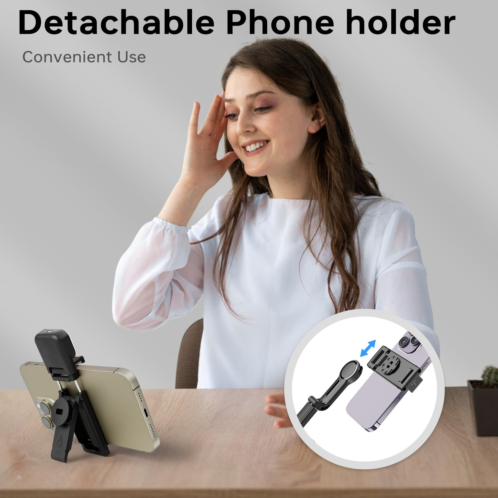 Eine Frau lächelt, hält ihre Hand in der Nähe ihres Kopfes. Ein Telefon ist in einem Halter auf einer Holzoberfläche.