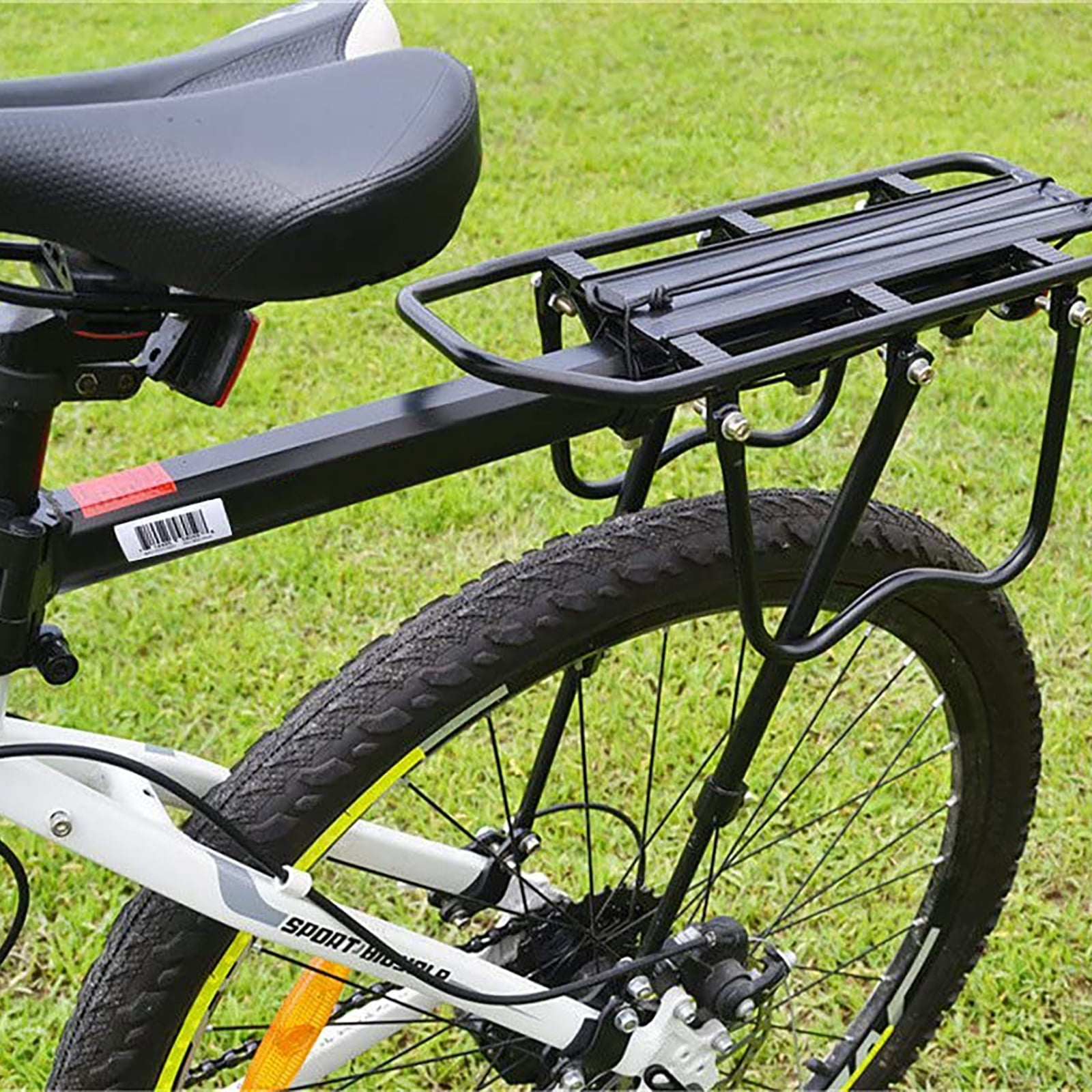 Schwarzes Fahrrad mit Gepäckträger auf grünem Gras. Der Fahrradsitz ist schwarz. Der Reifen ist schwarz.