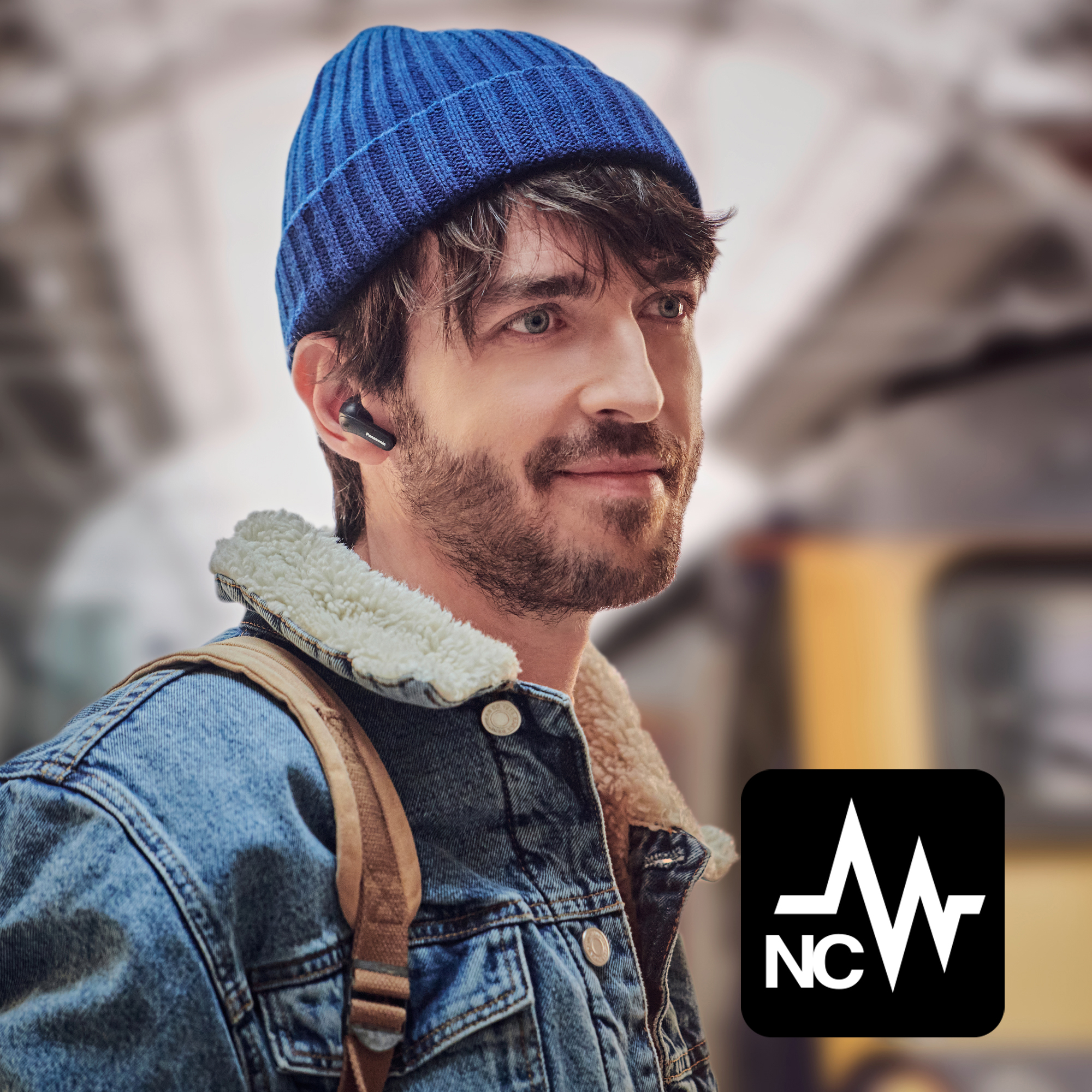 Mann mit blauer Mütze und Jeansjacke mit Ohrhörern. Er hat einen Rucksack. Ein Logo erscheint unten rechts.