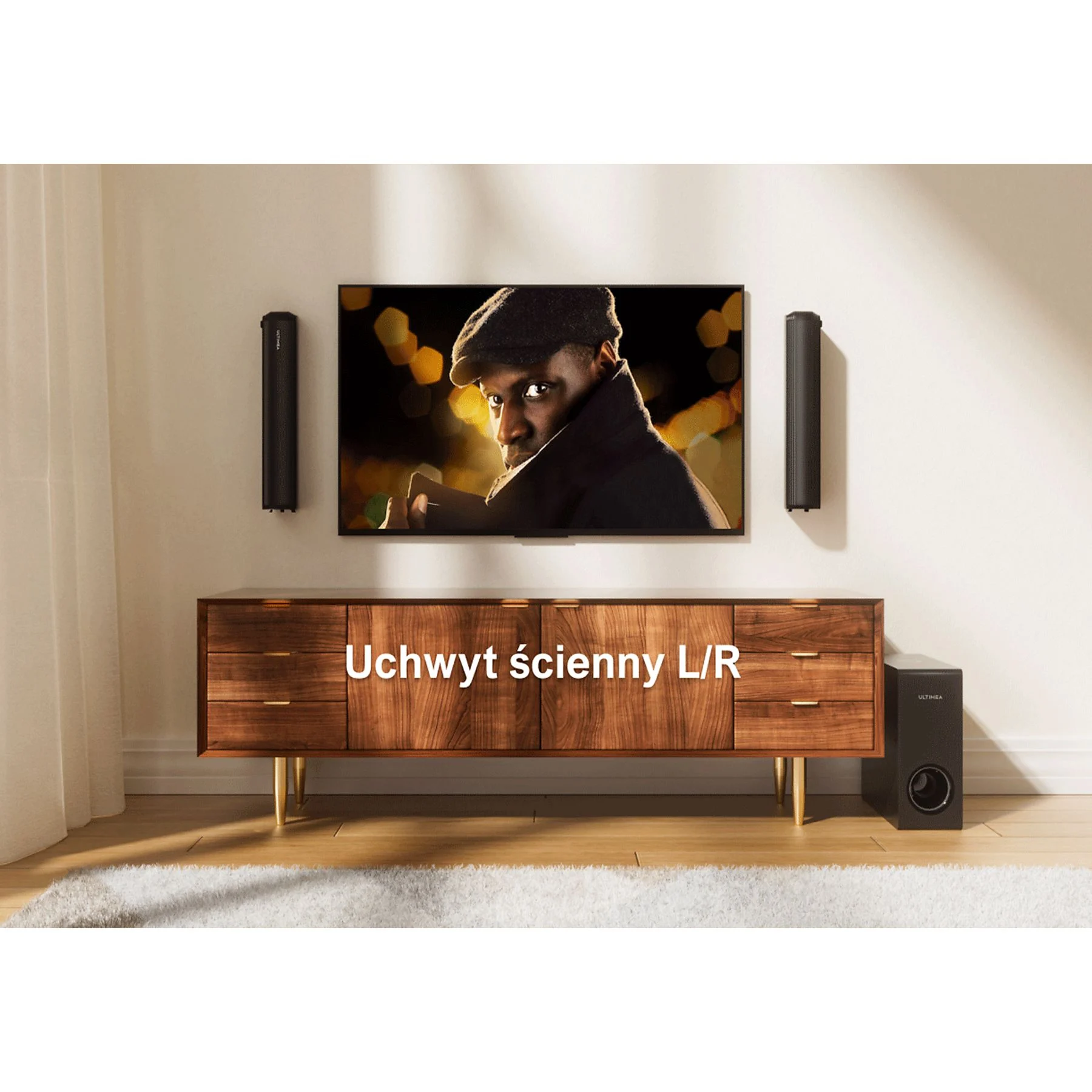 Salon z telewizorem, na którym widać mężczyznę. Widoczna jest również drewniana szafka, głośniki i subwoofer.