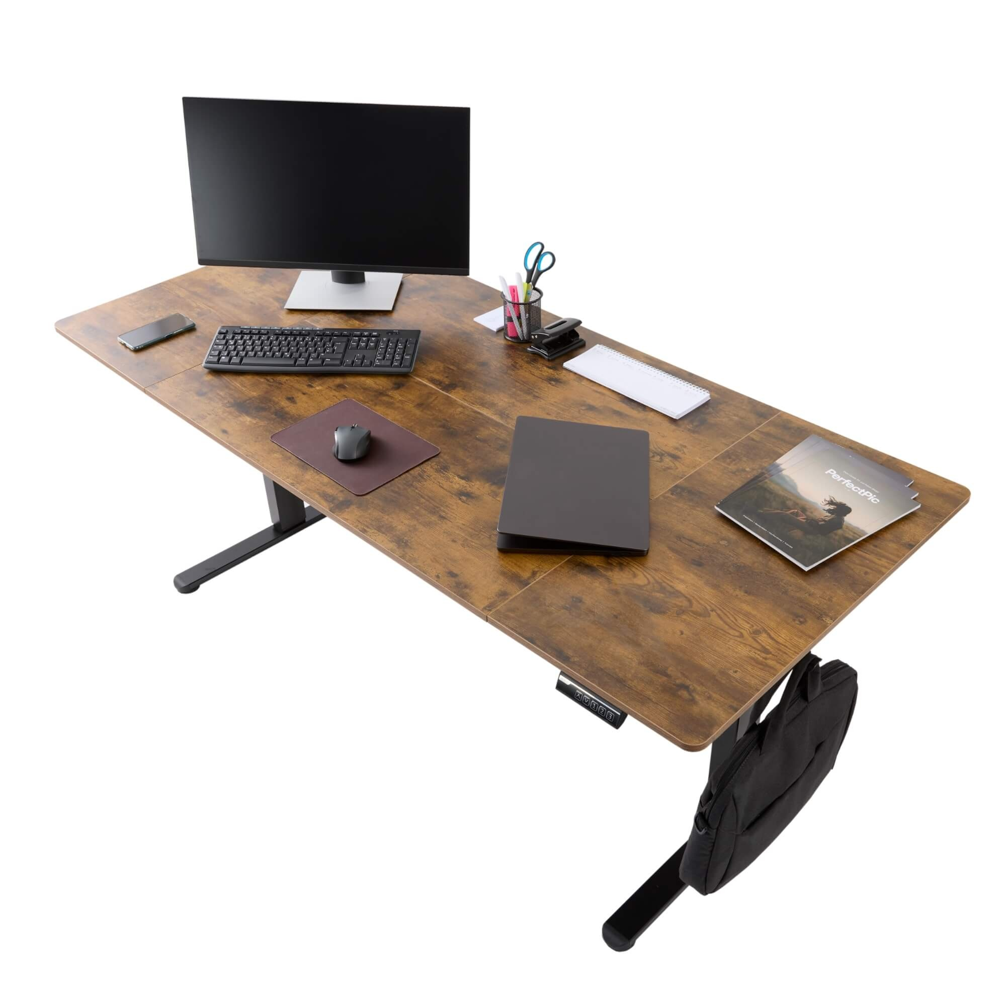 Holzschreibtisch mit Computer, Tastatur, Maus, Telefon und Zubehör. Eine schwarze Tasche hängt vom Schreibtisch.