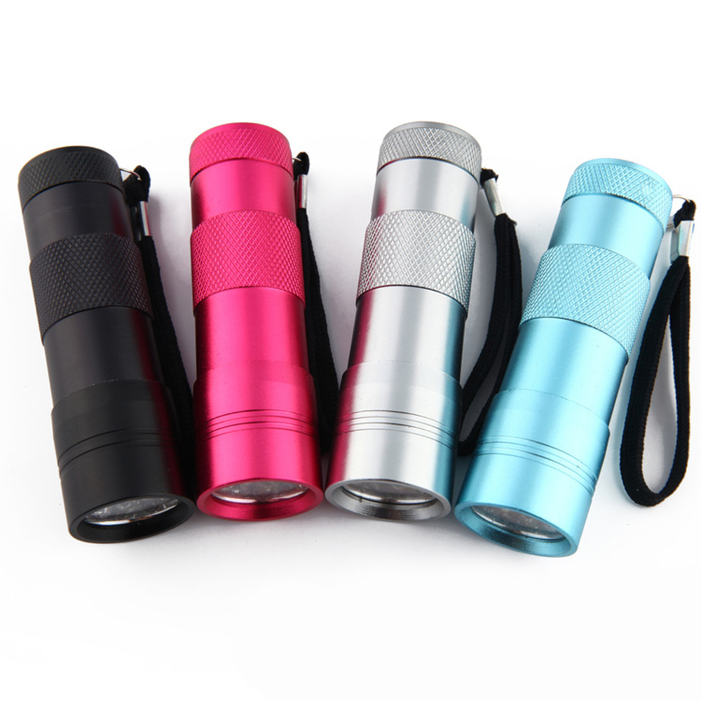 Vier farbige Taschenlampen: schwarz, rosa, silber und blau. Jede hat eine Handschlaufe und einen strukturierten Griff. Sie stehen auf weißem Grund.