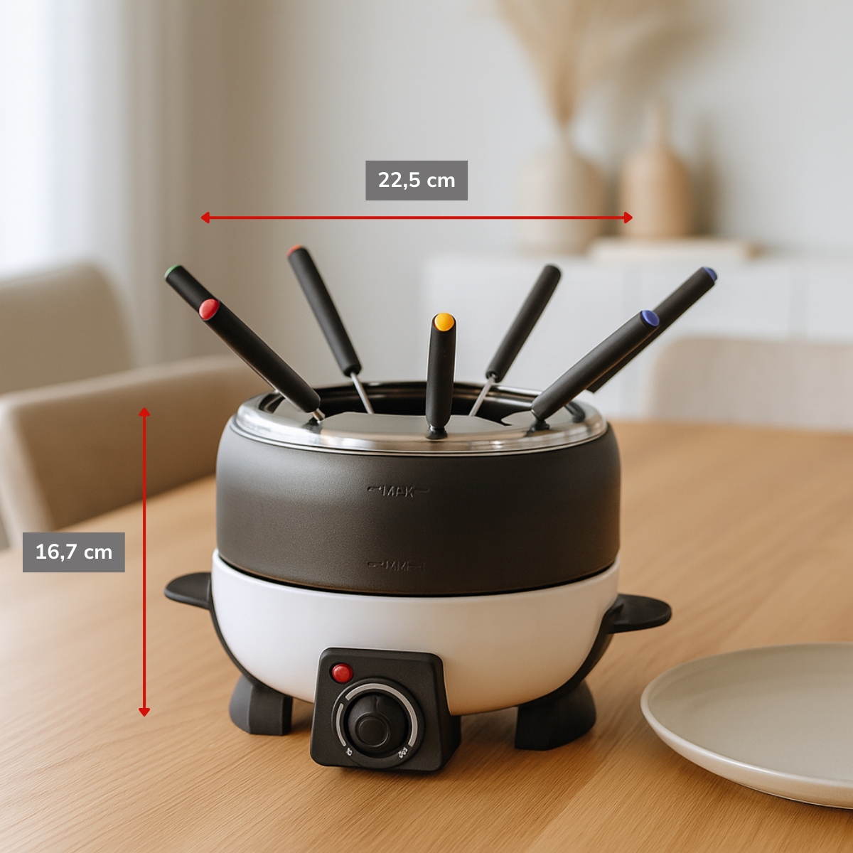 Un set per fonduta con corpo nero e bianco, diverse forchette con punte di colori diversi e un piatto. È su un tavolo di legno.