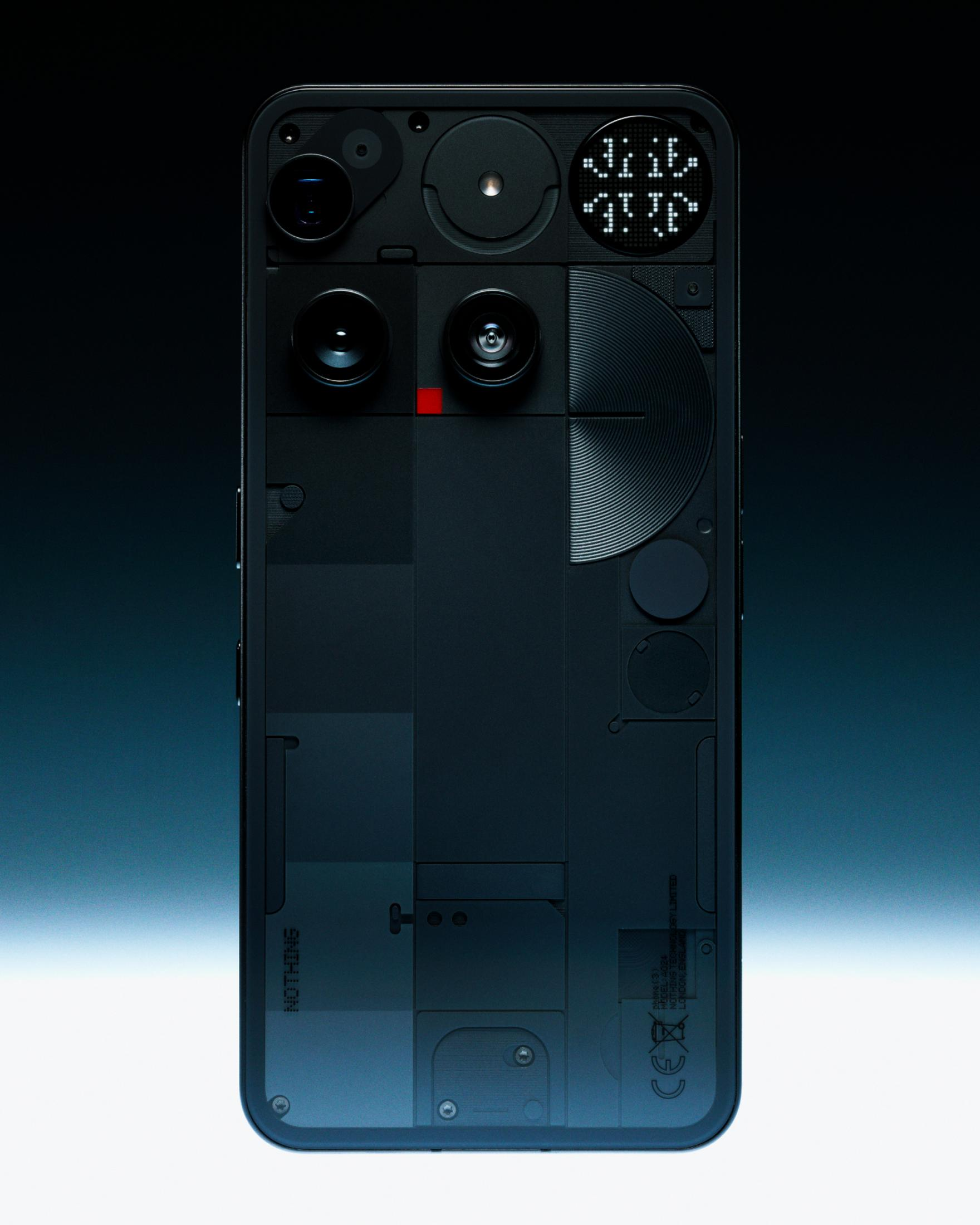 Tył czarnego smartfona, pokazujący wewnętrzne elementy. Obiektywy, diody LED i logo 'Nothing'.