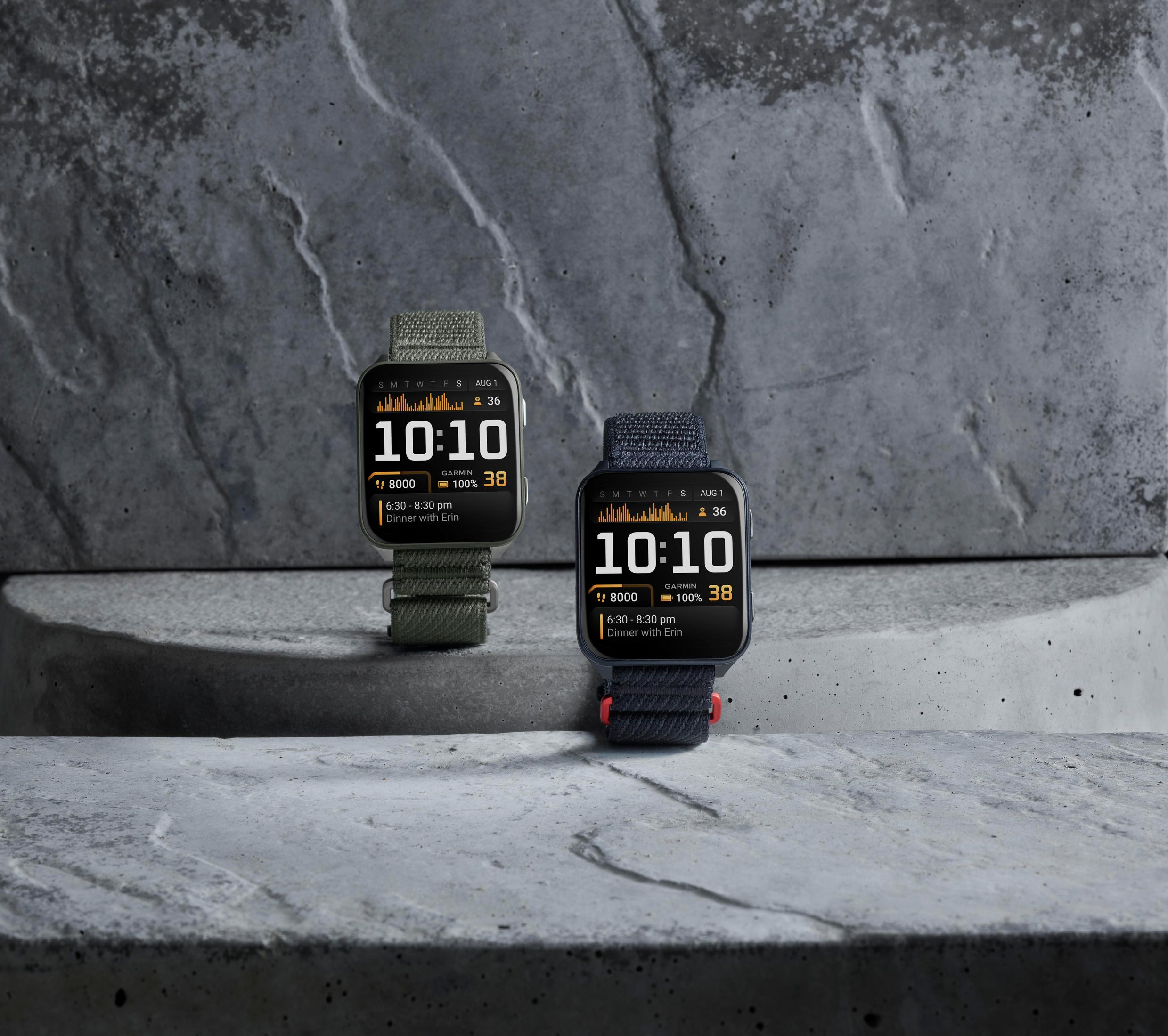Zwei Smartwatches auf Beton. Beide zeigen 10:10. Eine hat grüne, die andere blaue Armbänder.