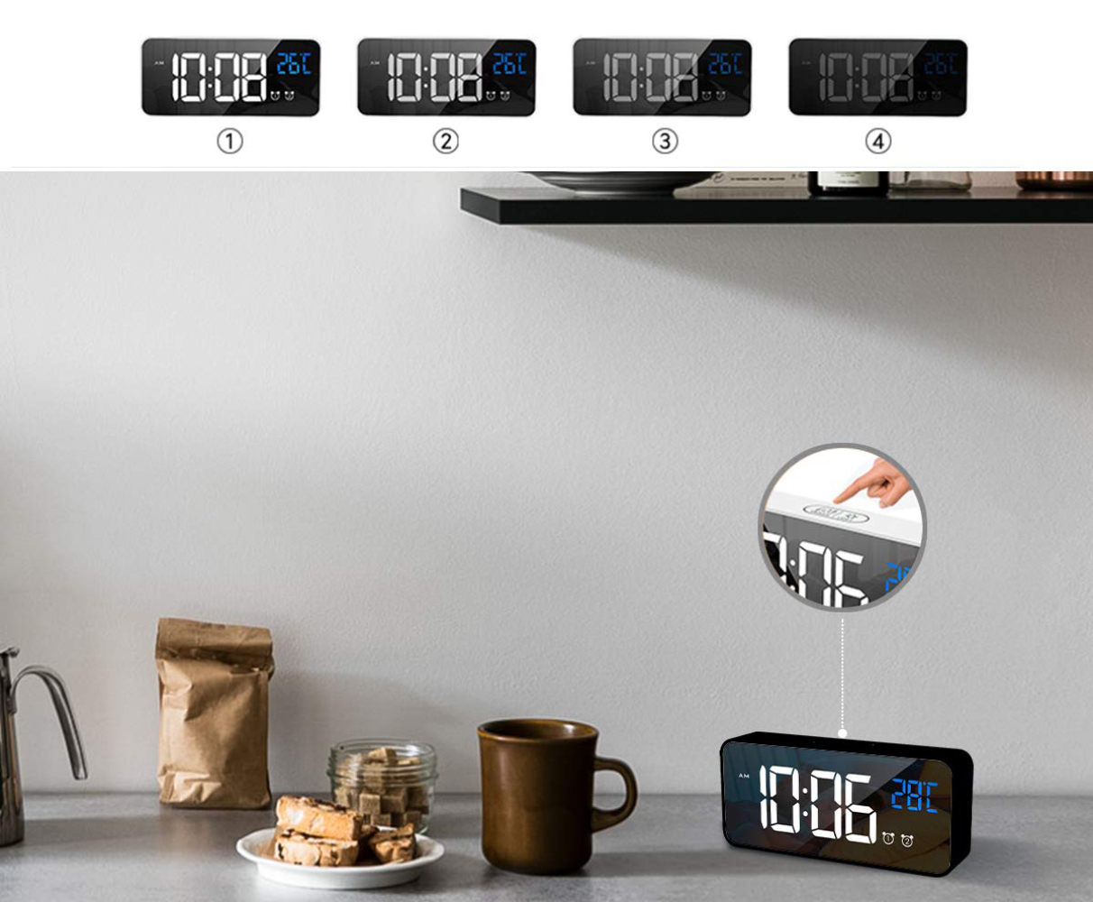 Eine Digitaluhr zeigt 10:06, 26C. Andere Uhren zeigen 10:08. Eine Hand berührt eine Uhrentaste. Eine Tasse, ein Beutel und Kekse sind sichtbar.
