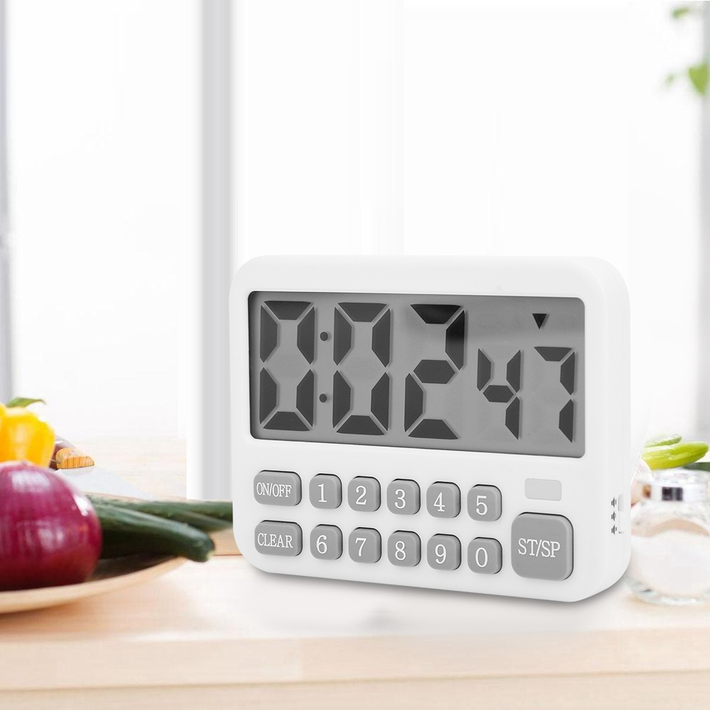 Ein weißer Küchentimer zeigt '00:24'. Er hat nummerierte Tasten und eine Start/Stopp-Taste. Gemüse ist im unscharfen Hintergrund.