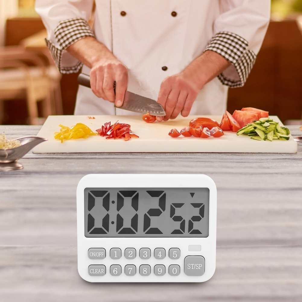 Ein Koch schneidet Tomaten auf einem Schneidebrett. Gehacktes Gemüse und ein Timer befinden sich im Vordergrund. Der Timer zeigt 0:02:52 an.