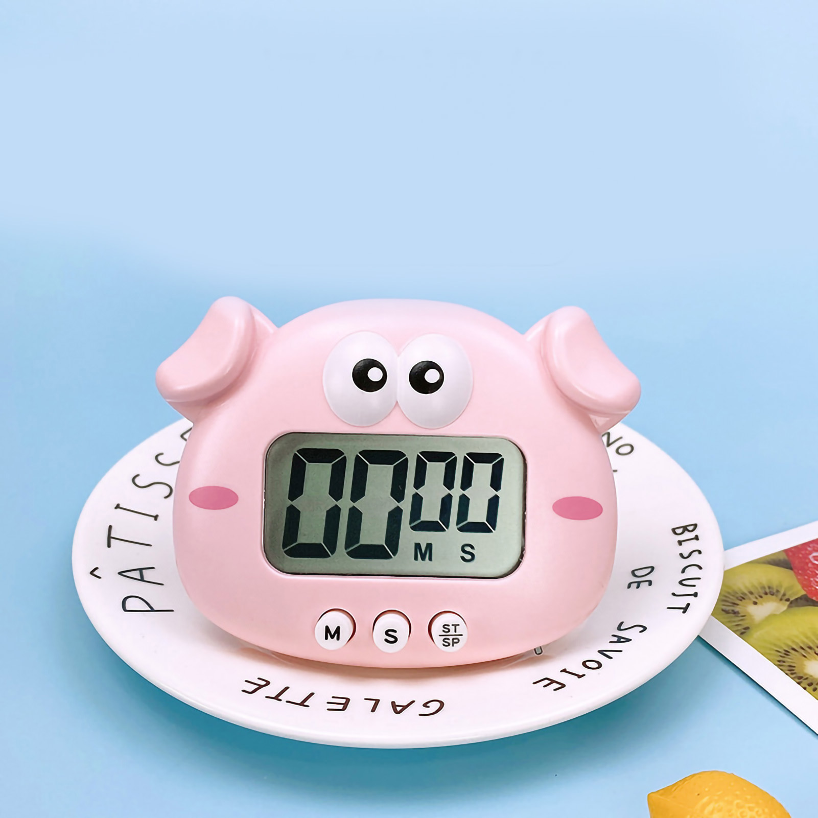 Ein rosa Schweine-Timer, der 00:00 anzeigt, auf einem weißen Teller. Der Hintergrund ist hellblau.
