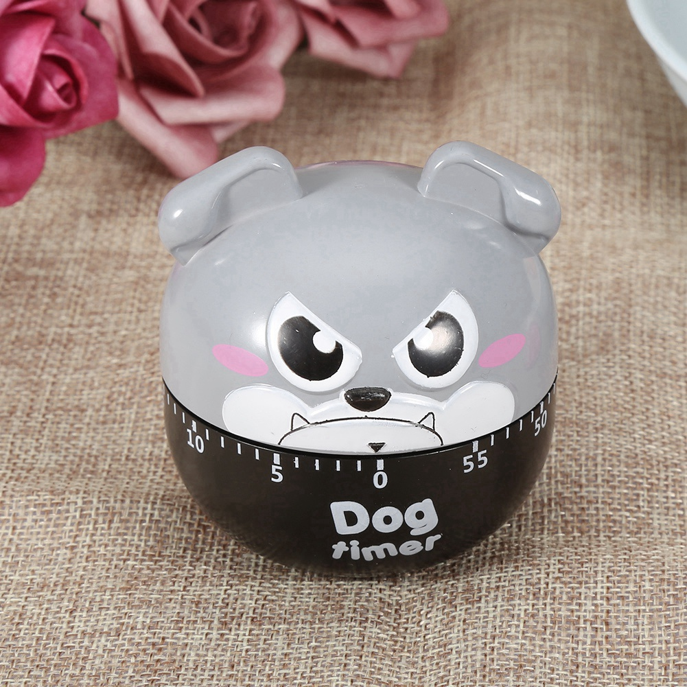 Ein hundeformiger Küchentimer. Er ist grau mit schwarzem Sockel und einer Skala. Der Hintergrund hat Rosen und einen braunen Stoff.