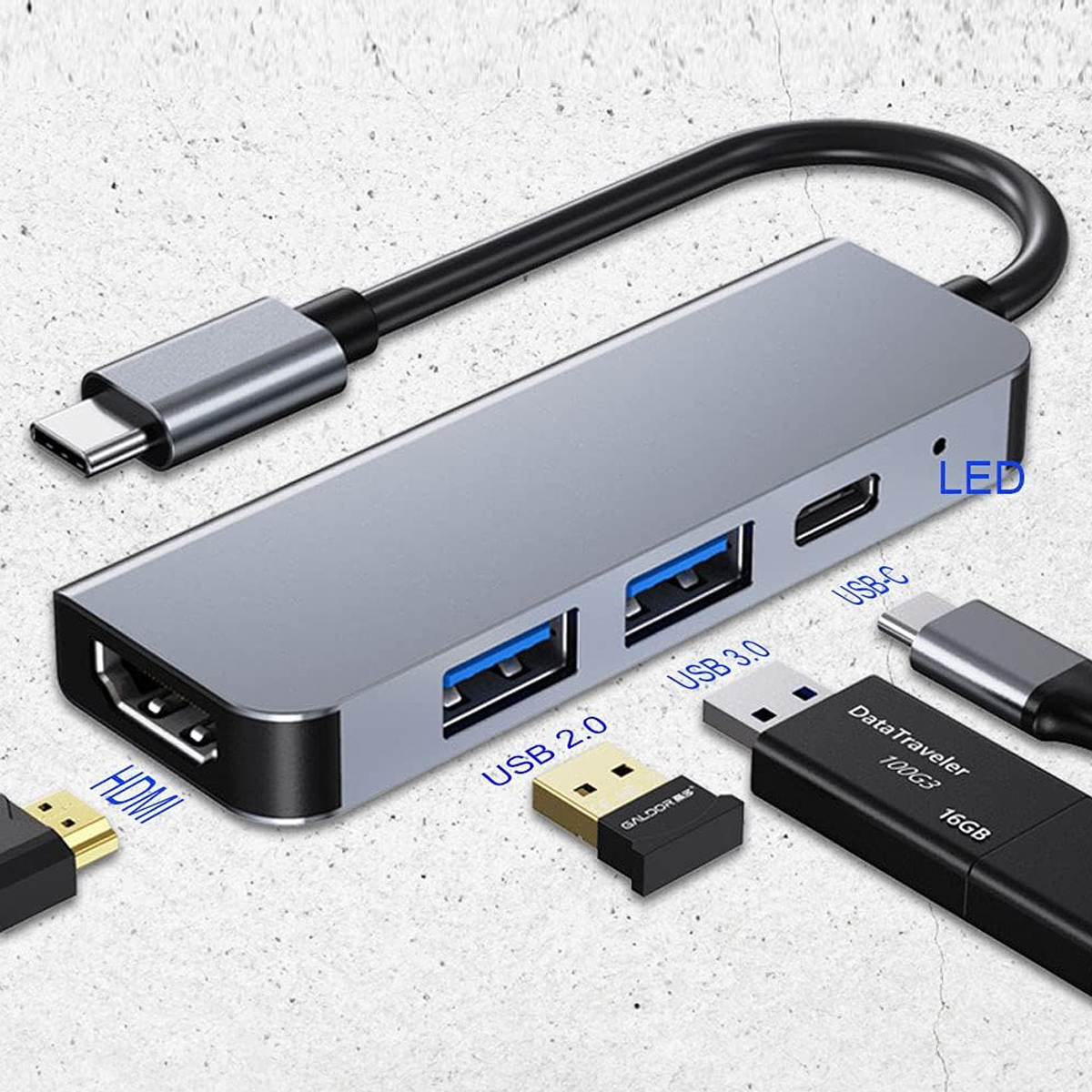 Ein silberner USB-Hub mit USB-Anschlüssen, einem USB-C-Anschluss und einem HDMI-Anschluss. USB-Sticks sind ebenfalls vorhanden.
