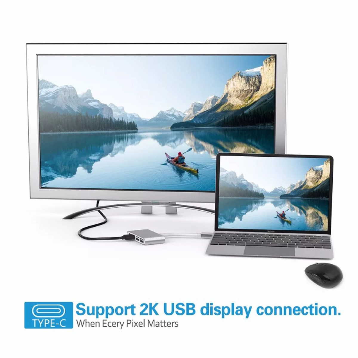 Ein Monitor, ein Laptop und eine Maus sind mit einem Hub verbunden. Beide Bildschirme zeigen eine Seeszene mit einem Kajakfahrer.