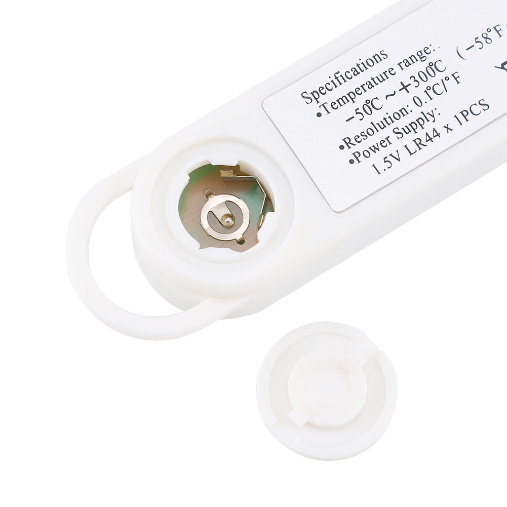 Ein weißes Thermometer mit offenem Batteriefach. Eine abgenommene Kappe befindet sich in der Nähe. Spezifikationen sind aufgedruckt.