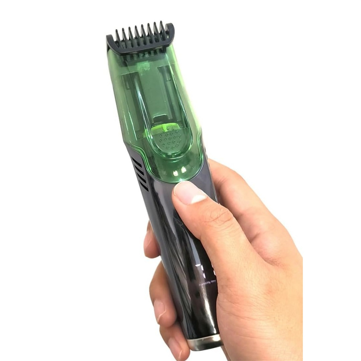 Hand hält einen schwarz-grünen elektrischen Haarschneider, Nahaufnahme. Der Trimmer hat einen Kammaufsatz.
