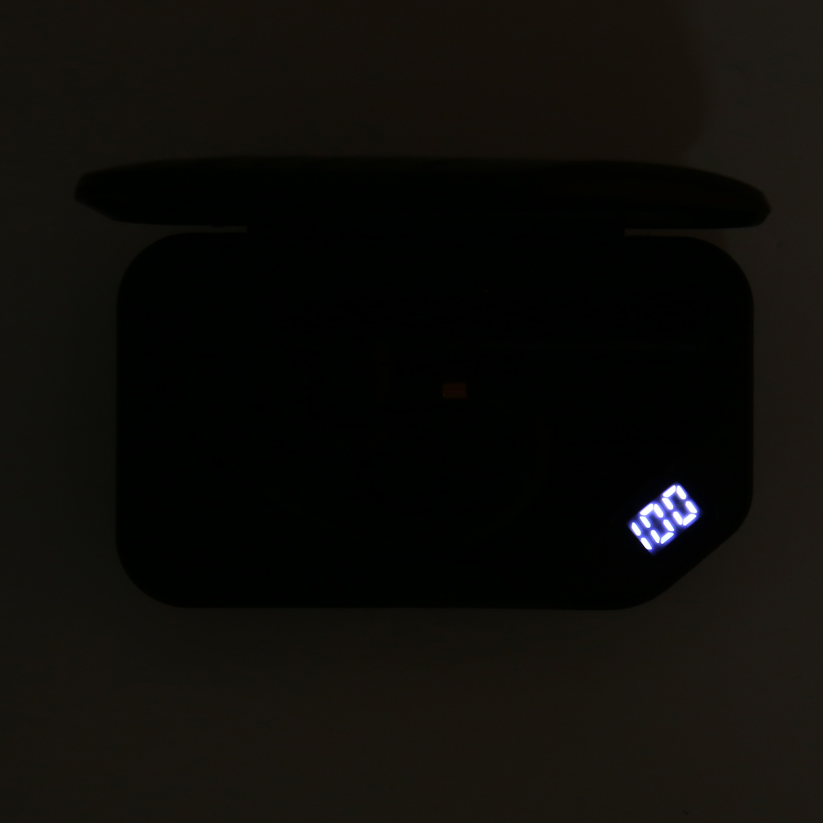 Eine schwarze Waage mit Digitalanzeige, die die Zahl 100 in hellem blauem Licht anzeigt.