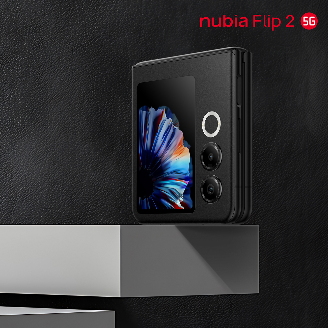 Czarny telefon nubia Flip 2 5G stoi na szarej podstawce na tle czarnego tła. Telefon jest otwarty, wyświetlając kolorowy ekran.