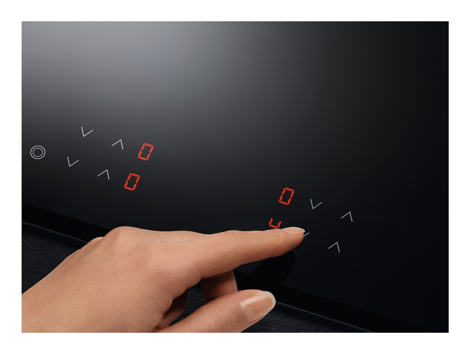 Una mano tocca un piano cottura nero. Vengono visualizzati i numeri rossi '0' e '4'. Sono visibili anche le frecce di controllo.