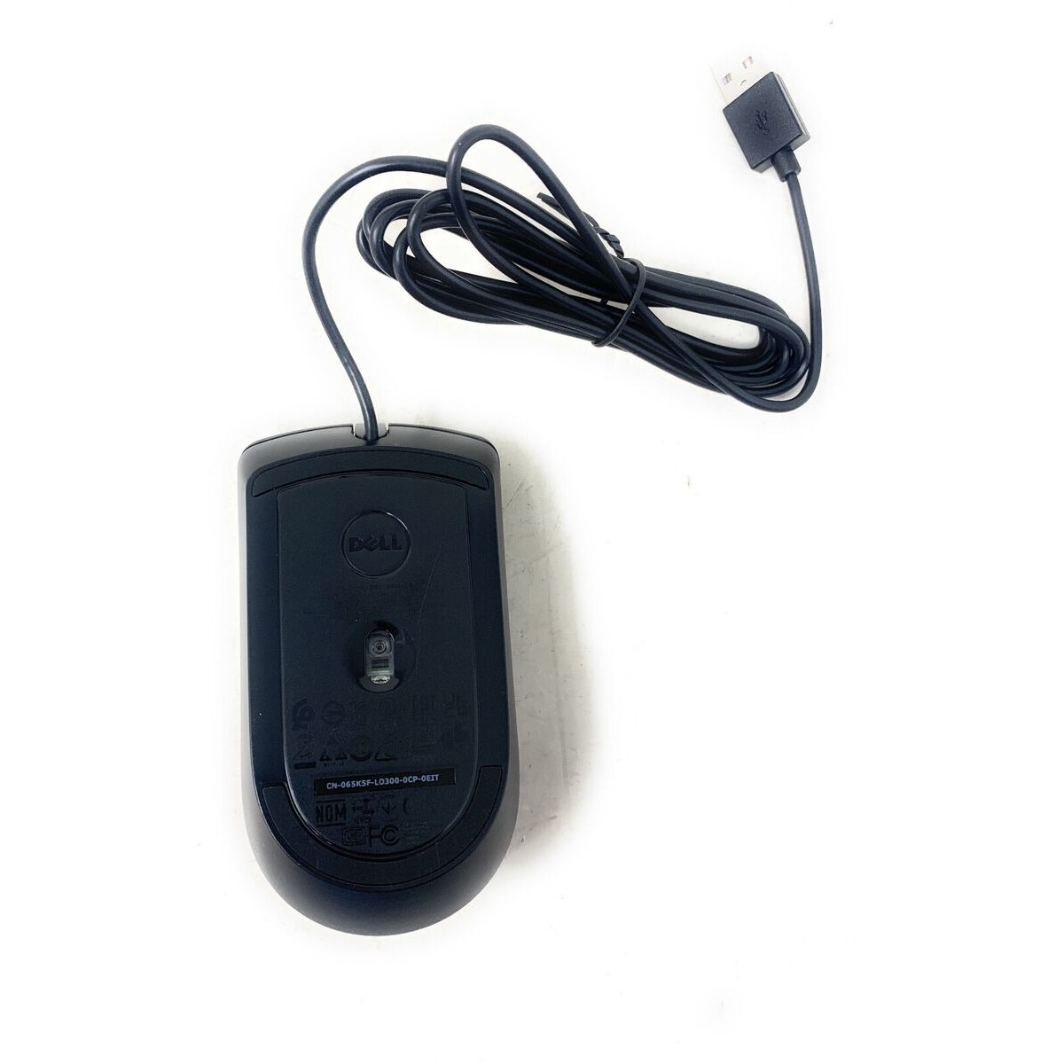 Ratón Dell negro con cable USB sobre superficie blanca. El ratón está boca abajo mostrando la parte inferior con el logo Dell.