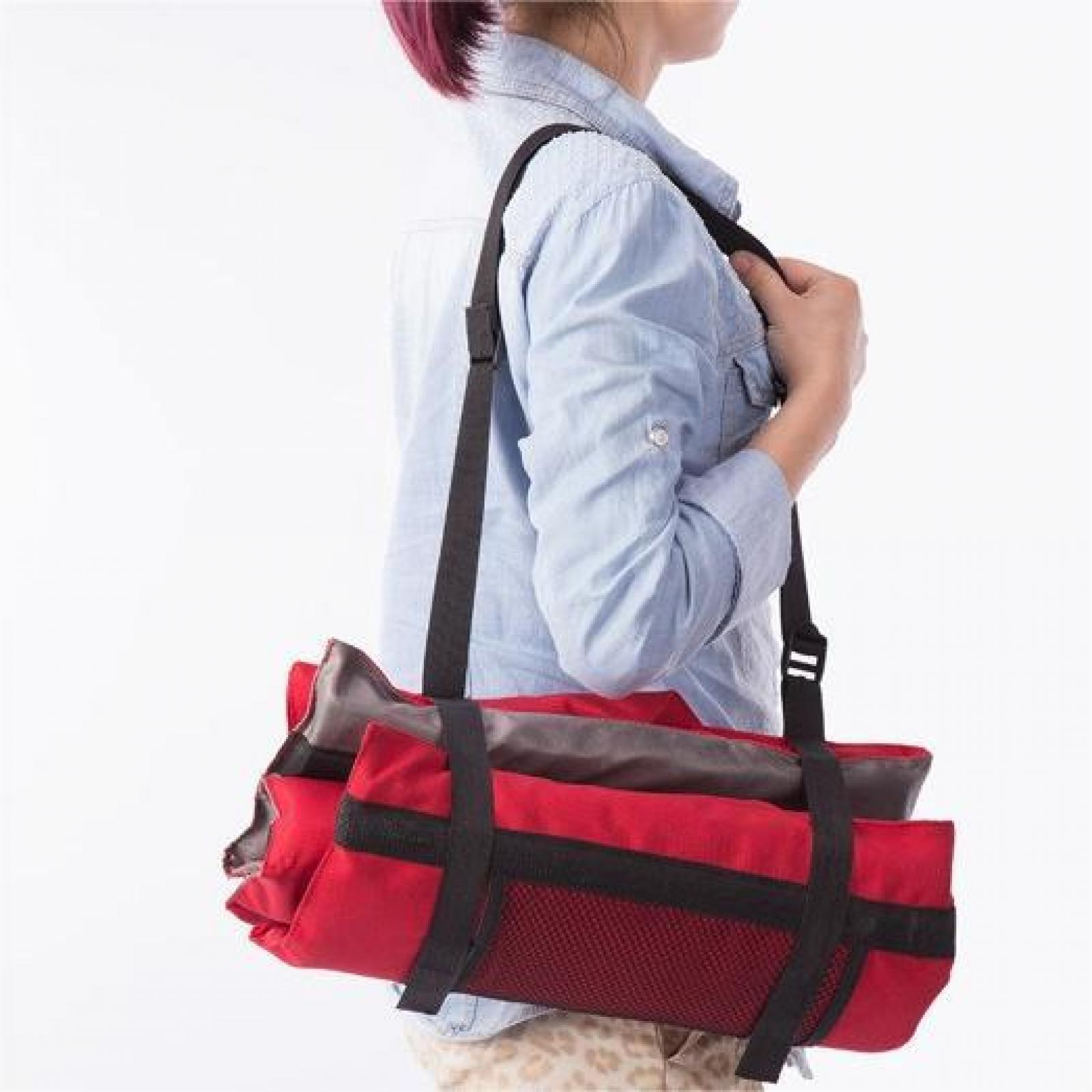 Eine Person trägt eine rot-graue Tasche mit schwarzen Trägern über der Schulter. Die Person trägt ein blaues Hemd.