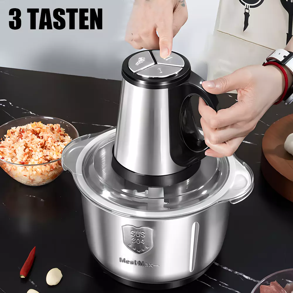 Eine Person bedient einen silbernen Foodprozessor. Gehacktes Essen liegt in einer Schüssel. Rote Paprika und Knoblauch liegen auf der schwarzen Theke.