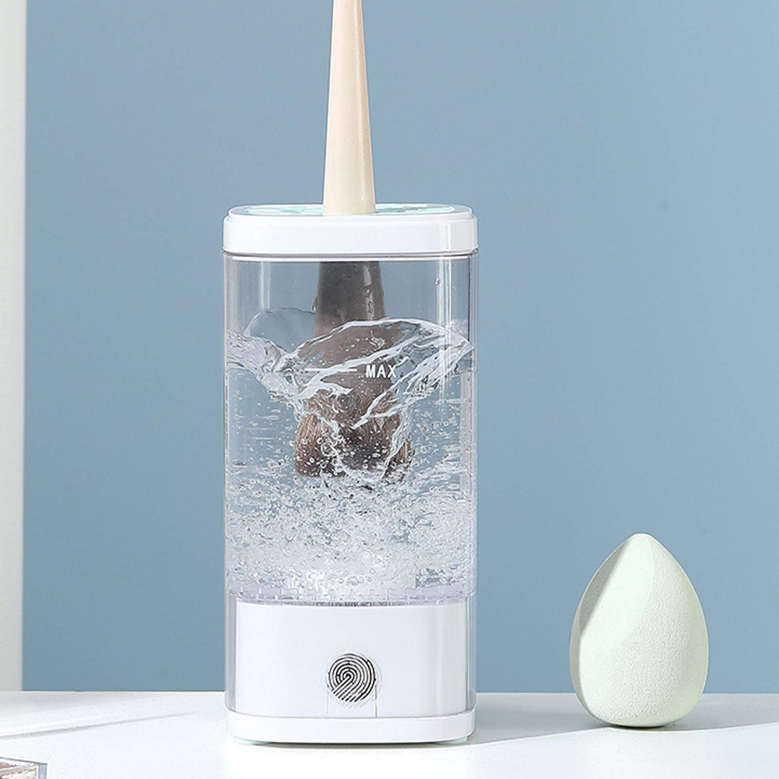 Eine weiße und transparente Reinigungsmaschine mit einer Bürste im Inneren, Wasserspritzern und einem grünen Schwamm an der Seite.