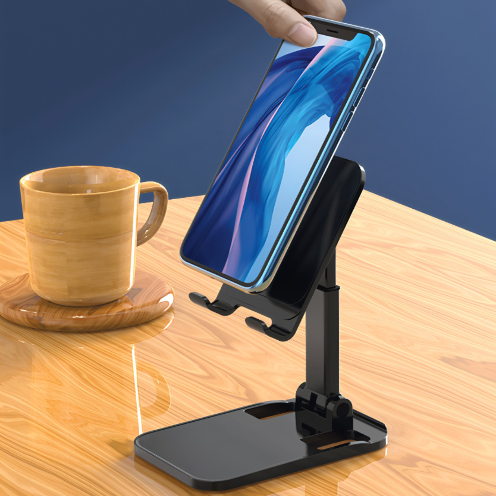 Eine Hand legt ein Telefon auf einen schwarzen Ständer. Daneben steht eine Tasse auf einem Untersetzer auf einem Holztisch. Blauer Hintergrund.