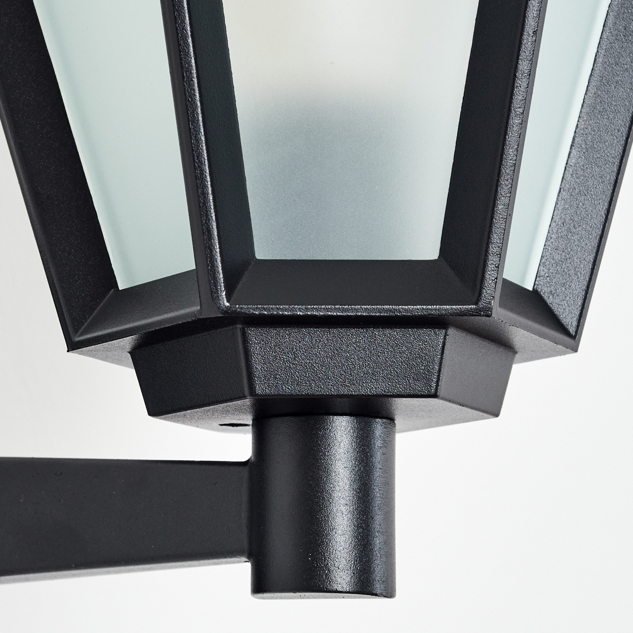 Nahaufnahme einer schwarzen Außenlampe. Die Lampe hat ein geometrisches Design mit Milchglasscheiben und einer strukturierten Oberfläche.