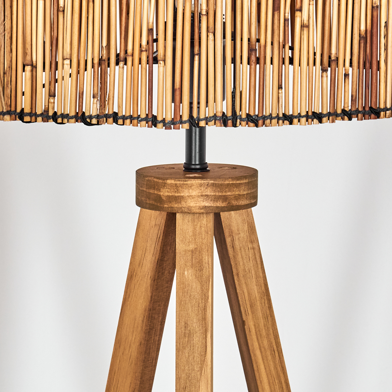 Eine hölzerne Stehlampe. Der Lampenschirm besteht aus Bambusstäben. Der Hintergrund ist schlicht weiß.
