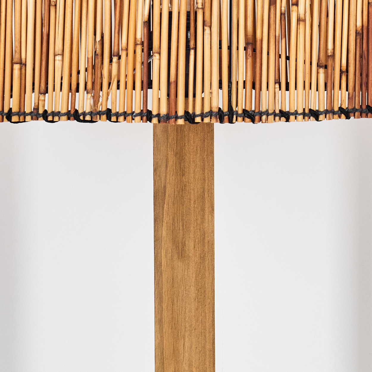 Eine Holzlampe mit Bambus-Lampenschirm. Der Holzpfahl ist braun, der Lampenschirm besteht aus vielen Bambusstäben.